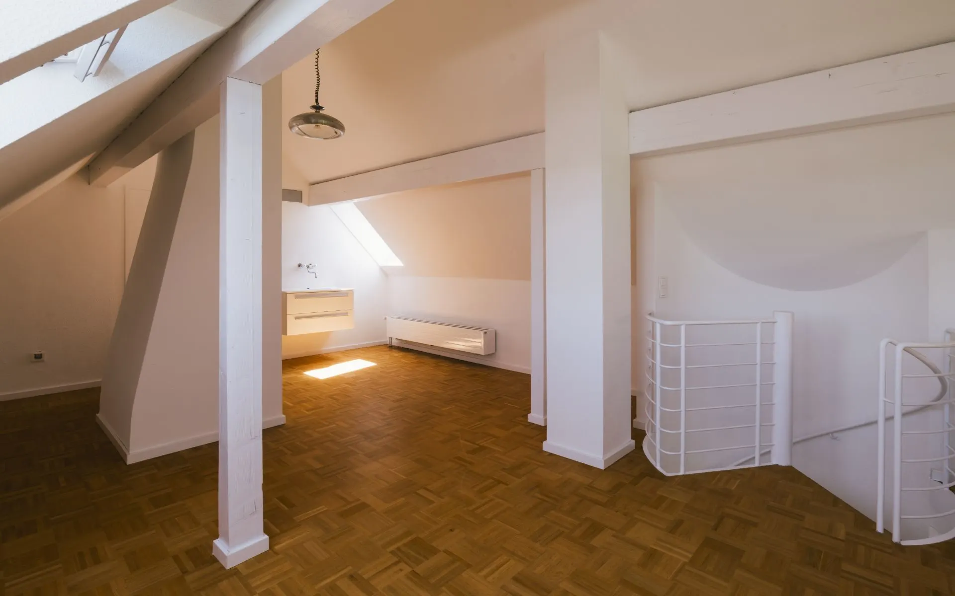 Heller Dachbodenraum mit Dachfenster, Holzboden, weißer Heizung und Geländer.
