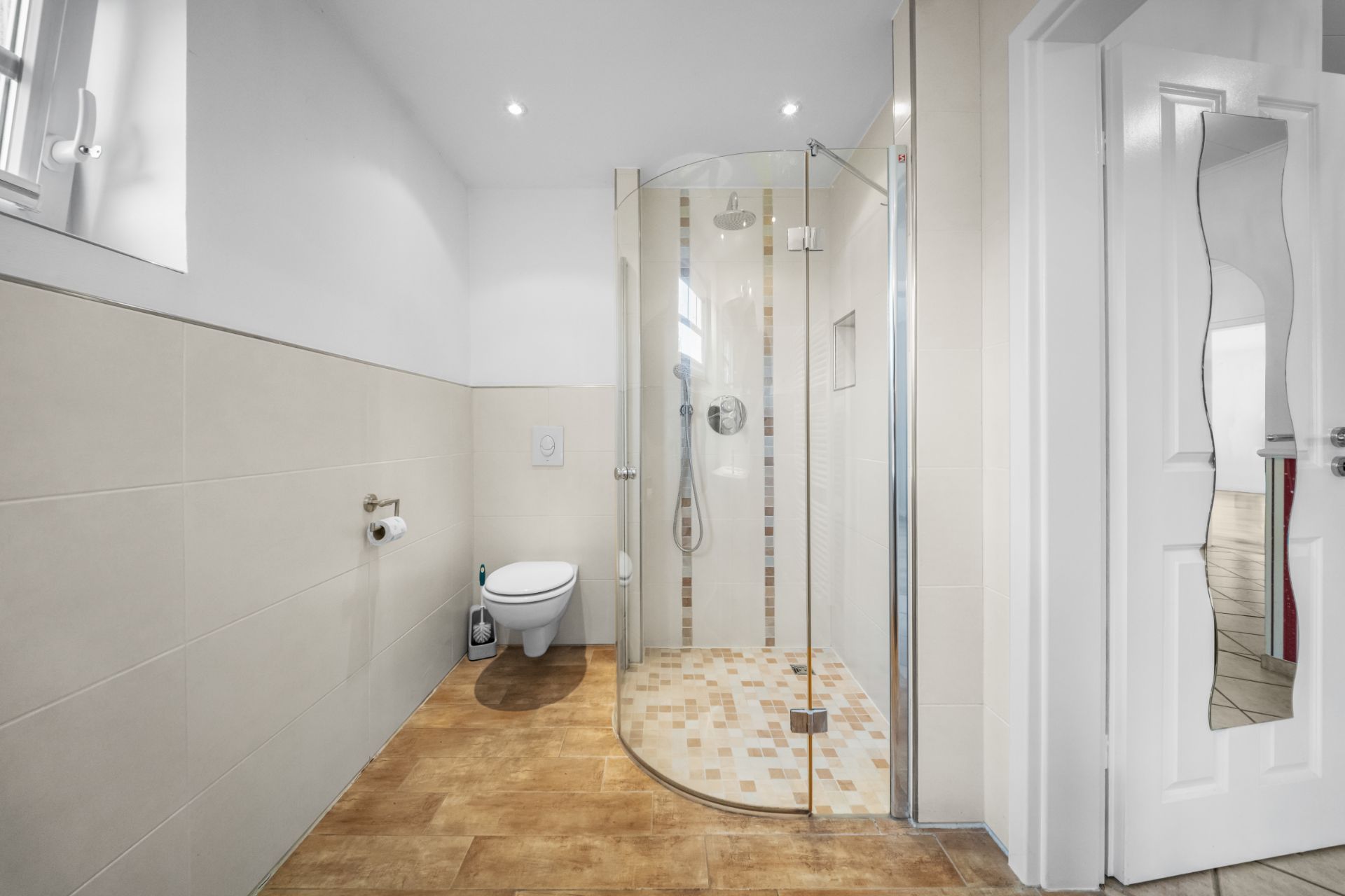 Modernes Badezimmer mit begehbarer Dusche, Wandtoilette und Fliesenboden.