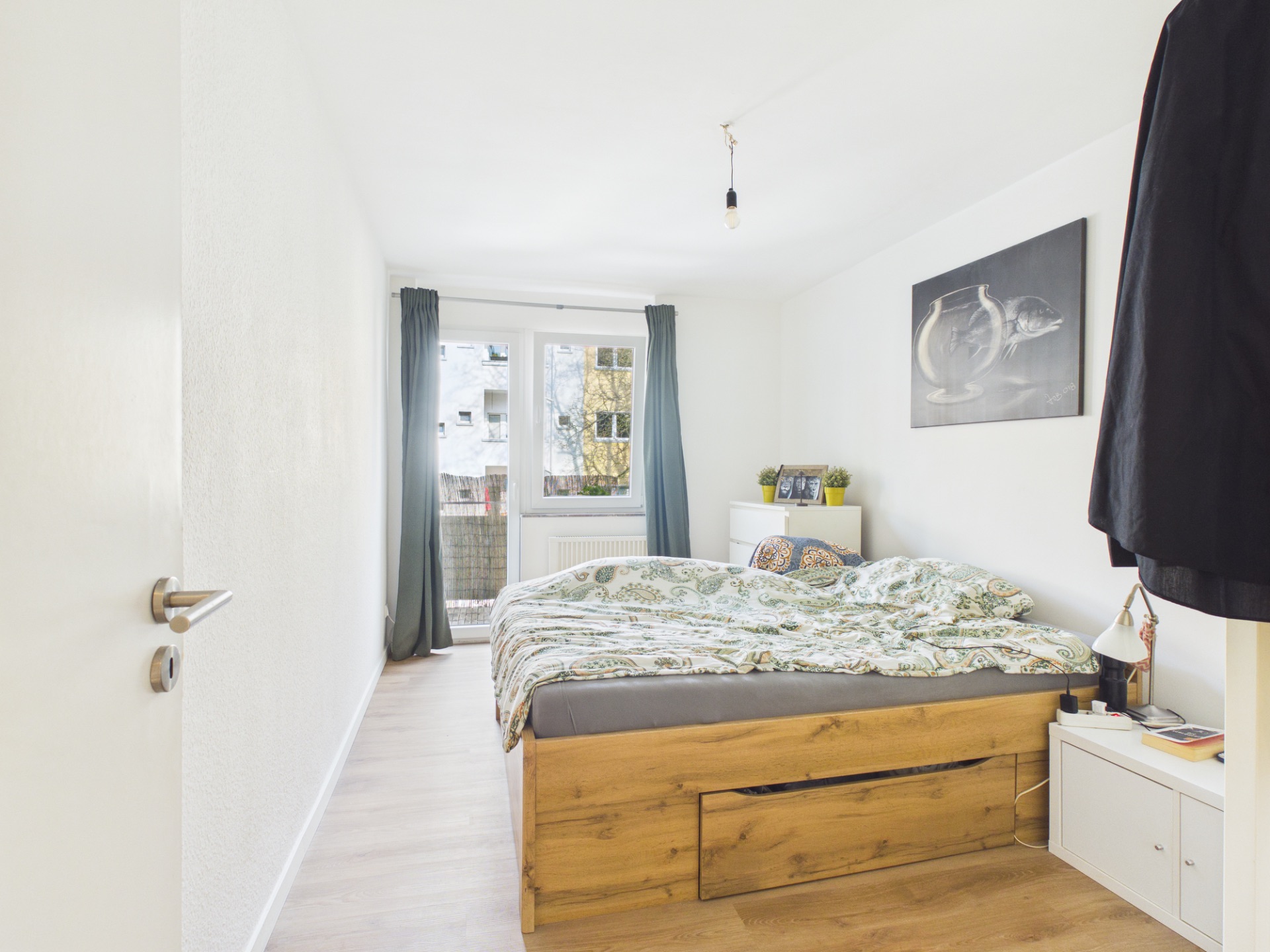 Helles Schlafzimmer mit Holzbett, Nachttischen und Zugang zum Balkon.