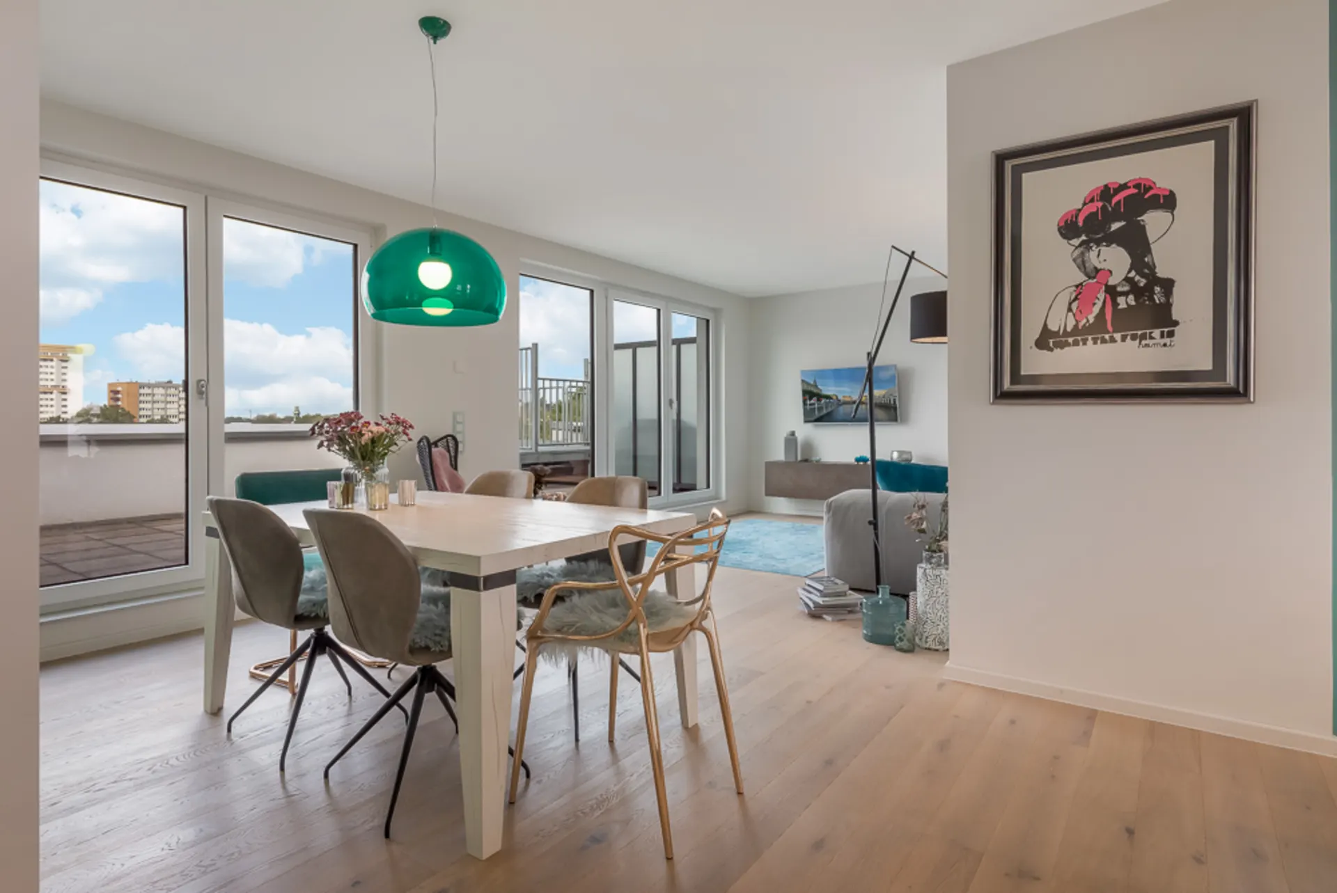 Modernes Ess- und Wohnzimmer mit Holzboden, großen Fenstern und grünem Lampenschirm.