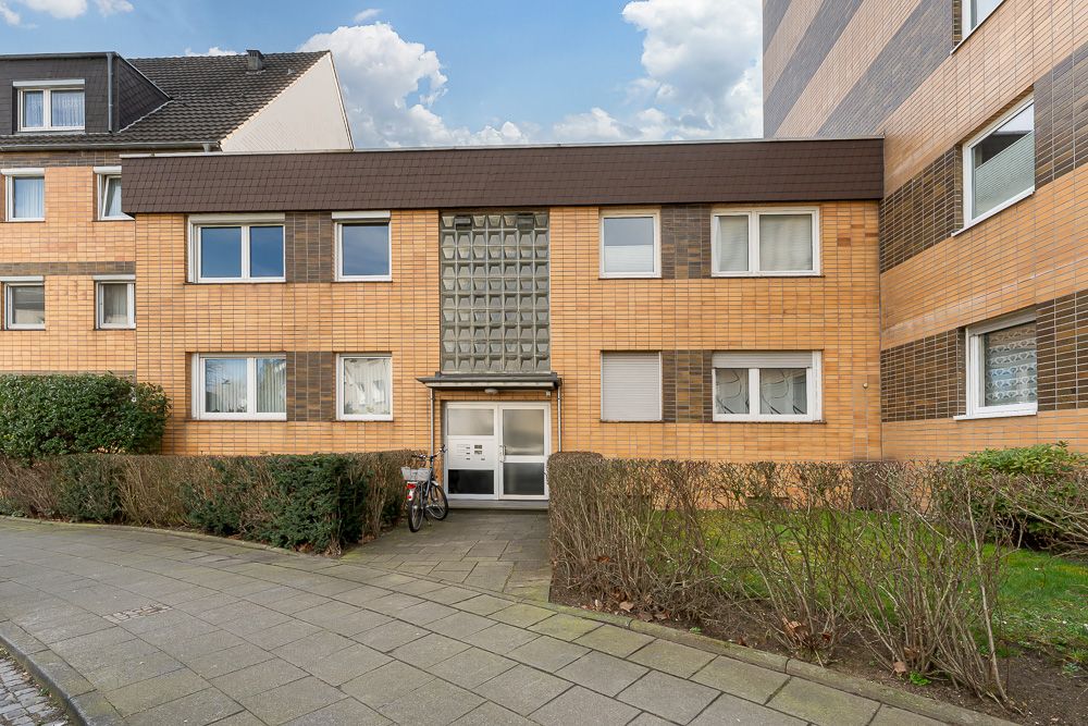 Eingang zu einem Mehrfamilienhaus mit gelber Klinkerfassade und einigen Fenstern.