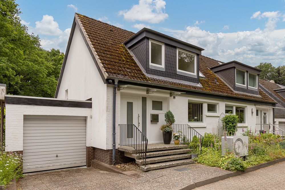 Doppelhaushälfte mit Garage, Vorgarten und Treppe zum Eingang.