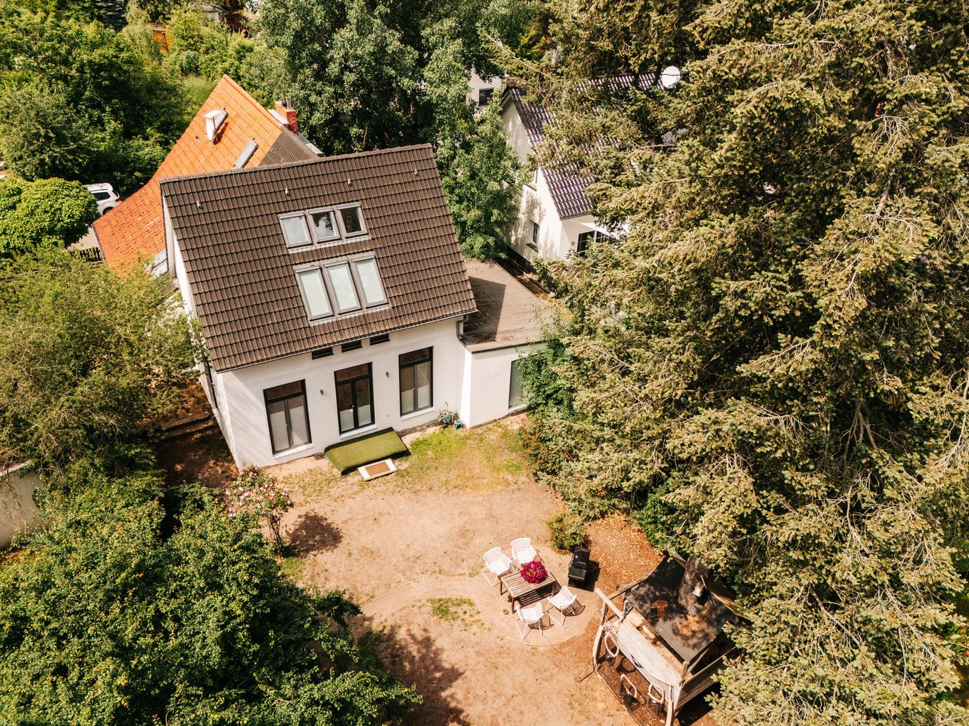 Luftaufnahme eines Hauses mit Garten, Sitzbereich und umgeben von Bäumen.