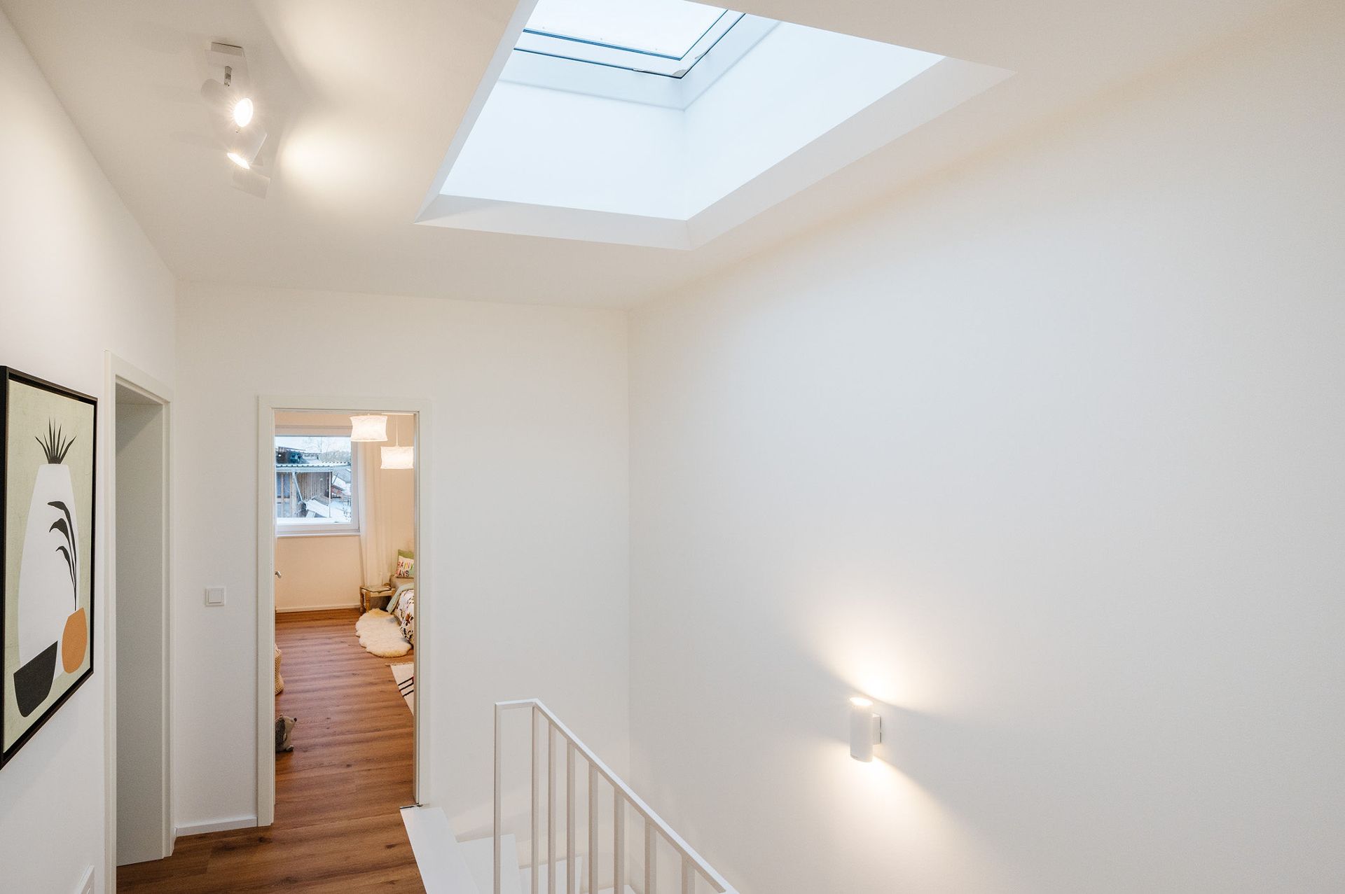 Heller Flur mit Oberlicht, Wandbild und Blick in wohnliches Zimmer mit Fenster.