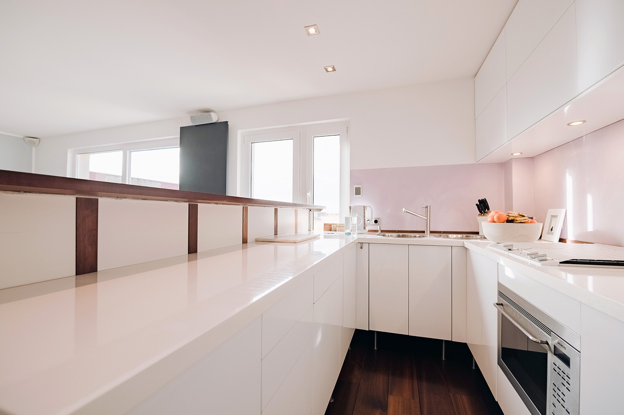 Helle, moderne Küche mit weißen Schränken, Holzdetails, Herd und Obstschale.