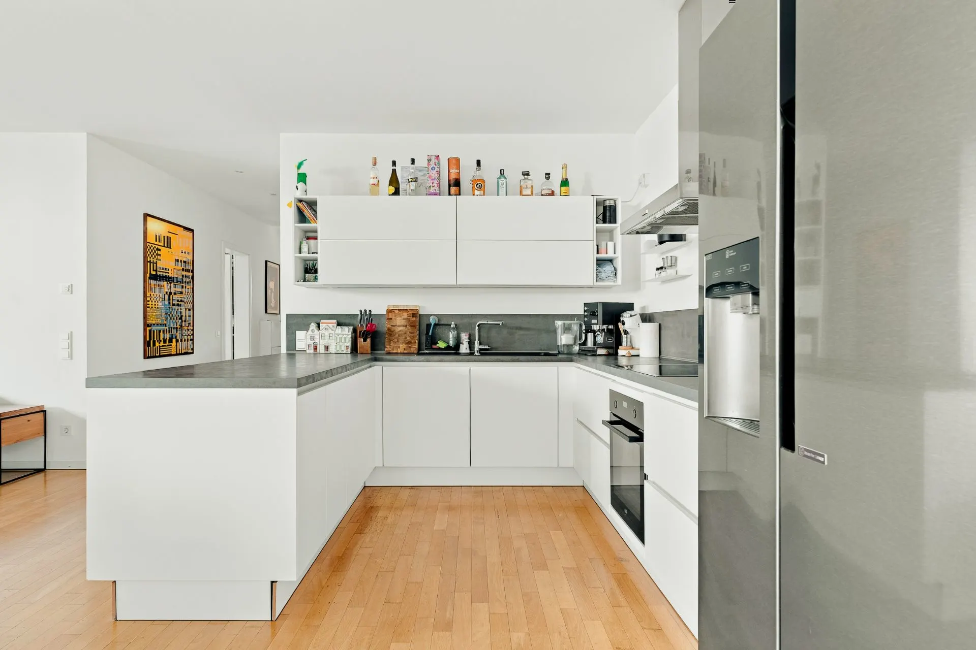 Moderne weiße Einbauküche mit Küchengeräten und Holzfußboden.