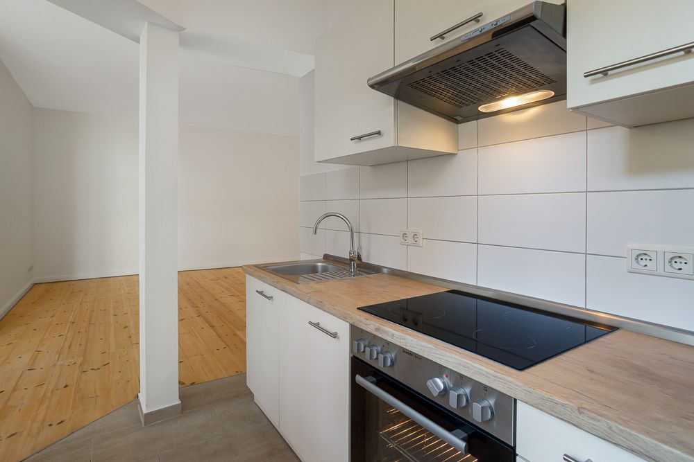 Moderne Einbauküche mit Herd, Spüle und Holzfußboden im offenen Wohnbereich.