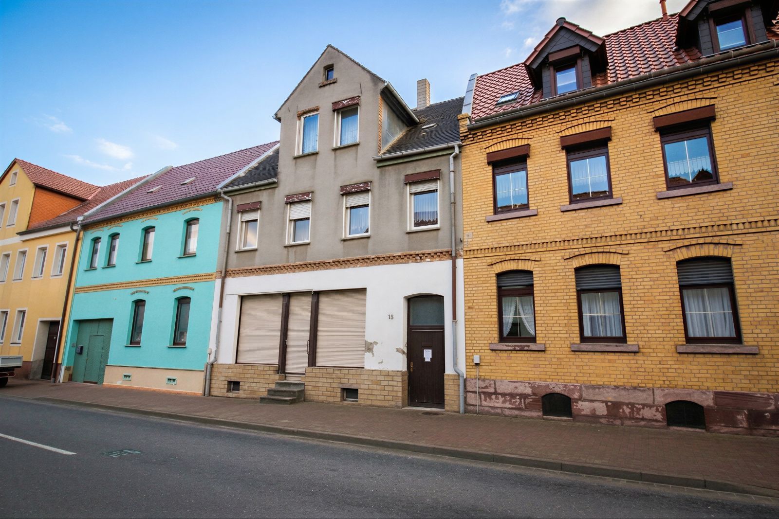 Mehrere Reihenhäuser mit verschiedenen Fassadenfarben an einer Straße.