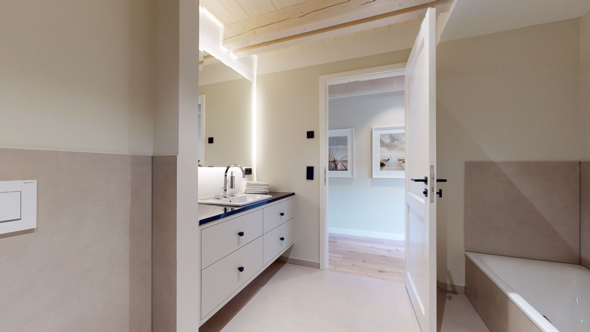 Modernes Badezimmer mit weißem Waschbecken, Spiegel und Badewanne, Tür ist geöffnet.