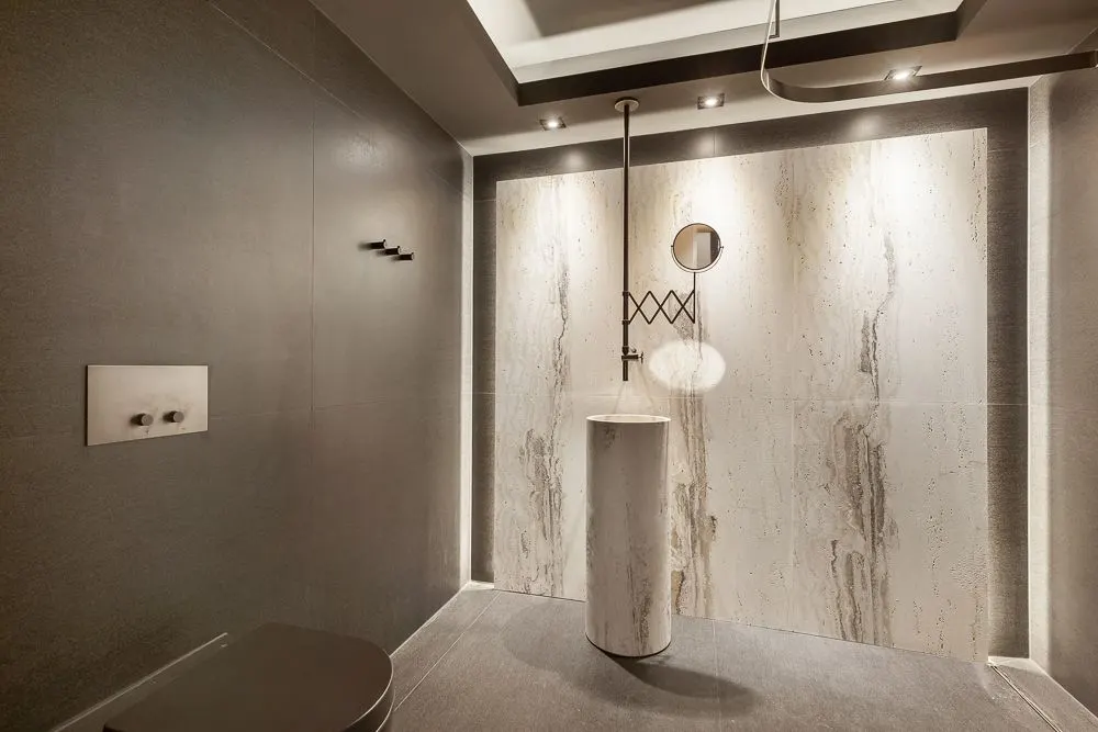 Modernes Badezimmer mit freistehendem Waschbecken und Rundspiegel vor heller Wand.