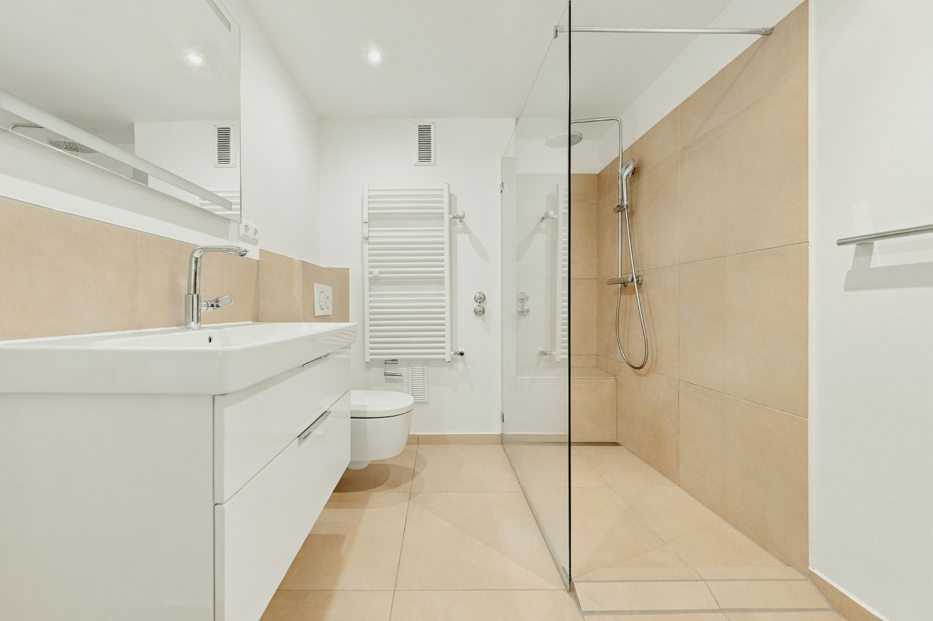 Modernes, helles Badezimmer mit begehbarer Dusche, Waschbecken und Wandtoilette.