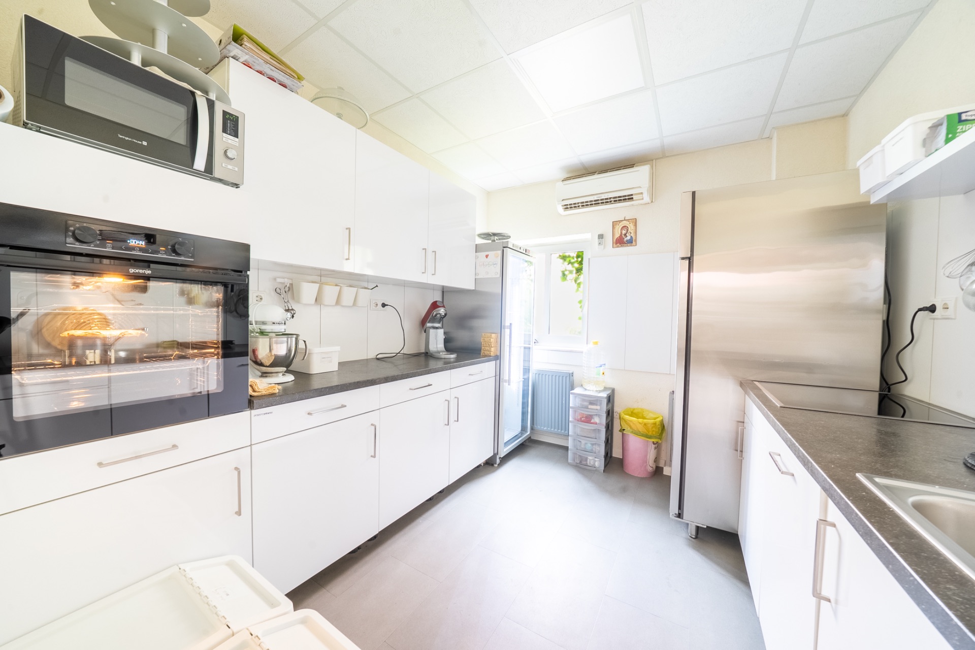 Helle, moderne Küche mit weißen Schränken, Backofen, Mikrowelle und großem Kühlschrank.