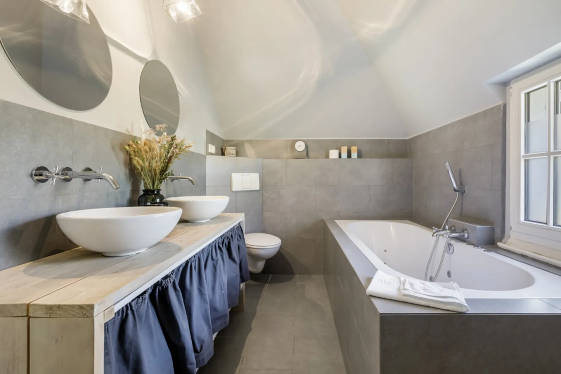 Modernes Badezimmer mit zwei Waschbecken, Badewanne, WC und großen Spiegeln.