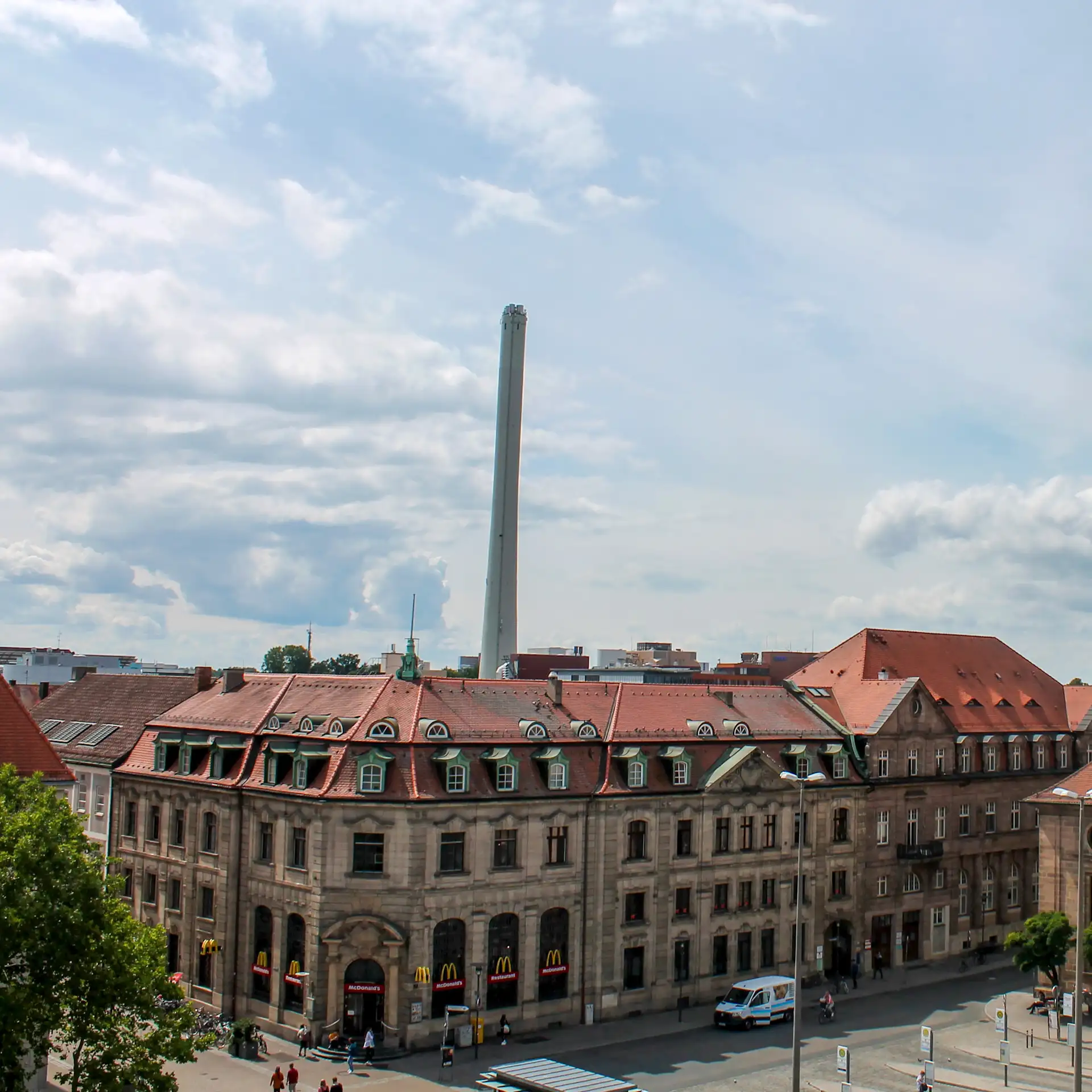 Blick auf ein großes, altes Gebäude mit rotem Dach und McDonald's-Filiale im Erdgeschoss.