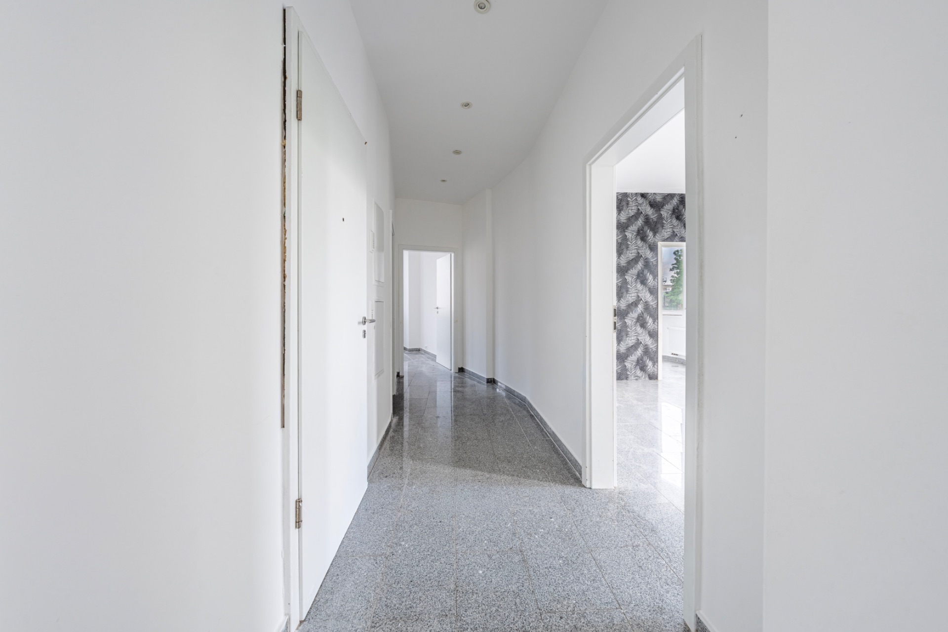 Heller Flur mit weißen Wänden und mehreren Türen in einer Wohnung.