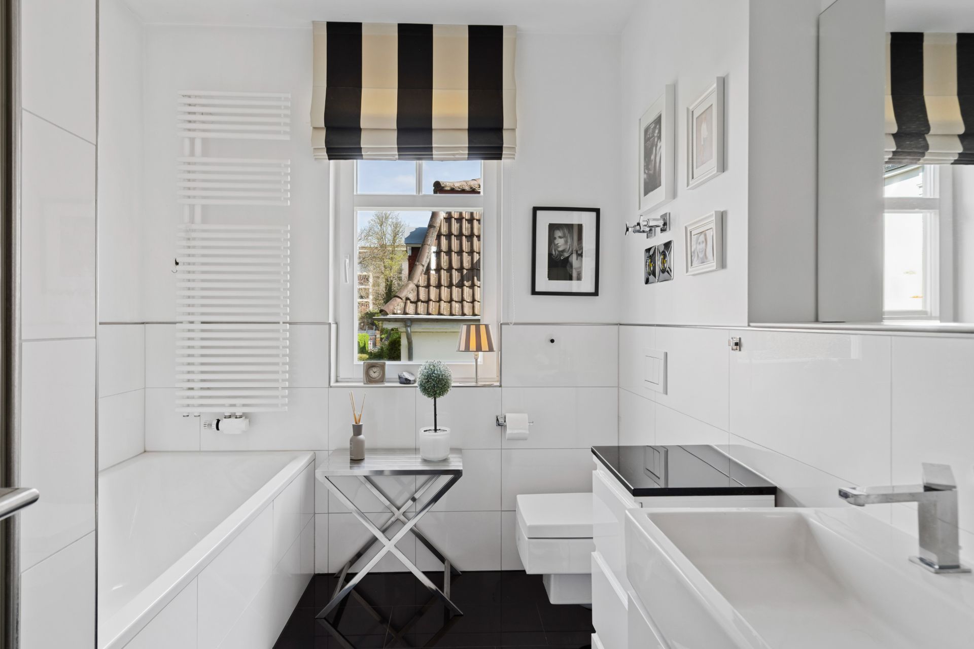 Modernes Bad mit Badewanne, Waschbecken, Toilette und Fenster mit gestreiftem Rollo.