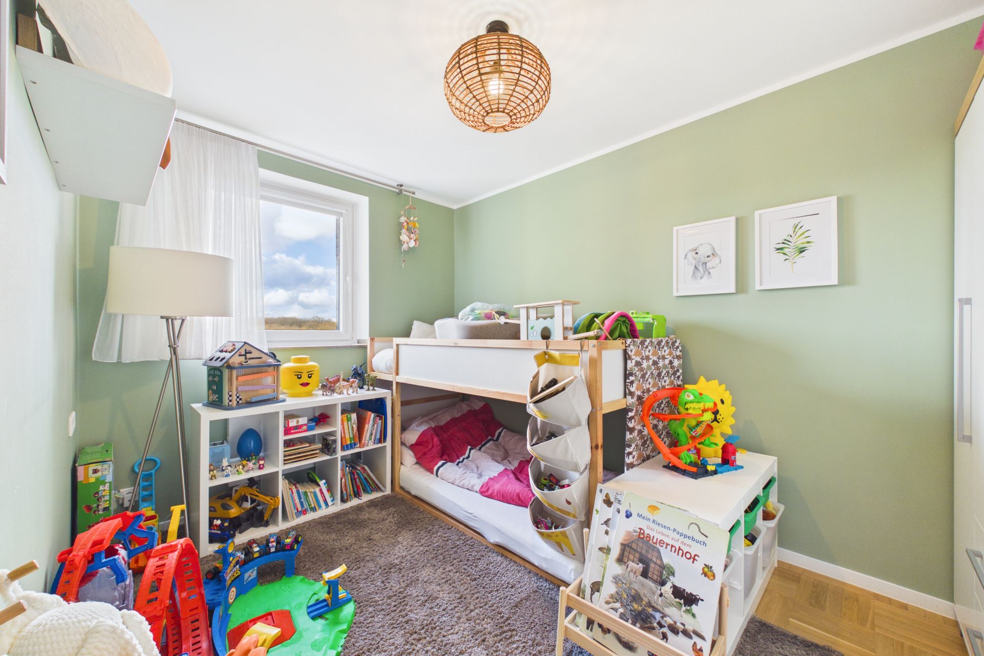 Kinderzimmer mit Etagenbett, Spielzeug, Regal und grün gestrichener Wand.