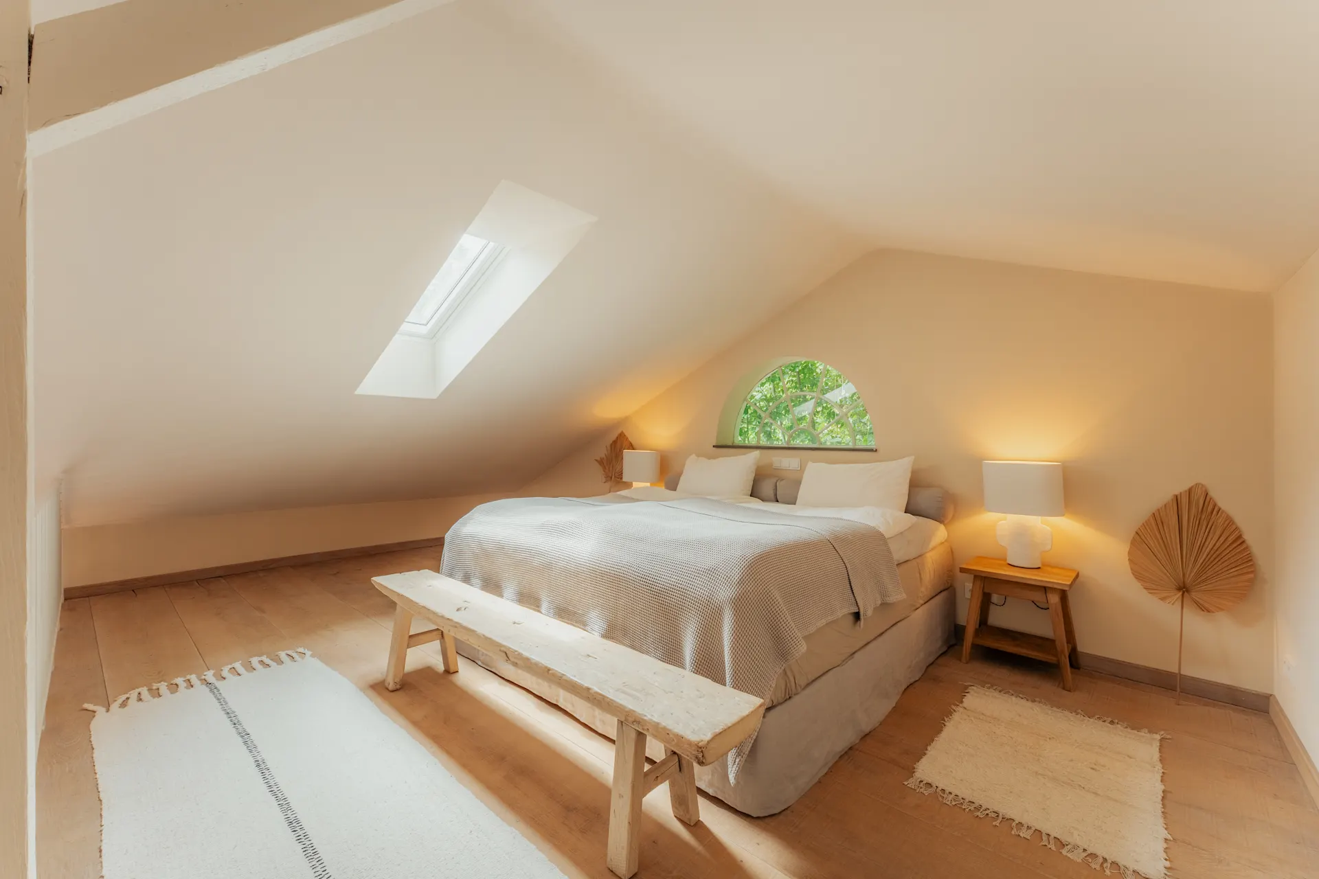 Helles Schlafzimmer mit Doppelbett, Holzboden, Dachschräge und Dachfenster.