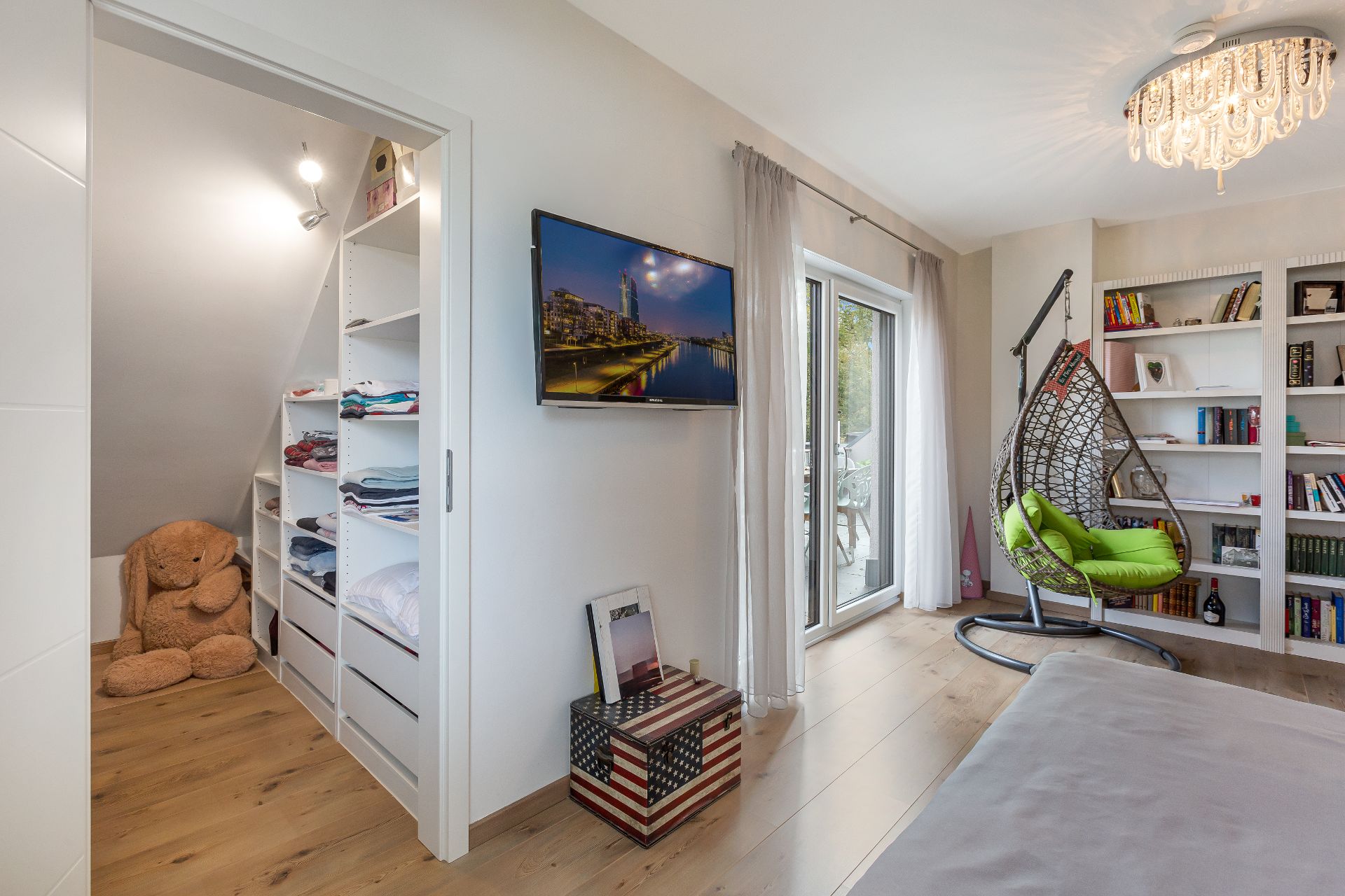 Modernes Schlafzimmer mit TV, Hängesessel, Bücherregal und begehbarem Kleiderschrank.