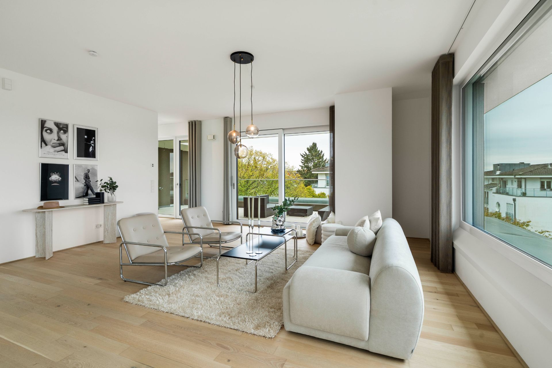 Modernes Wohnzimmer mit Sofa, Sesseln, Couchtisch und großen Fenstern.