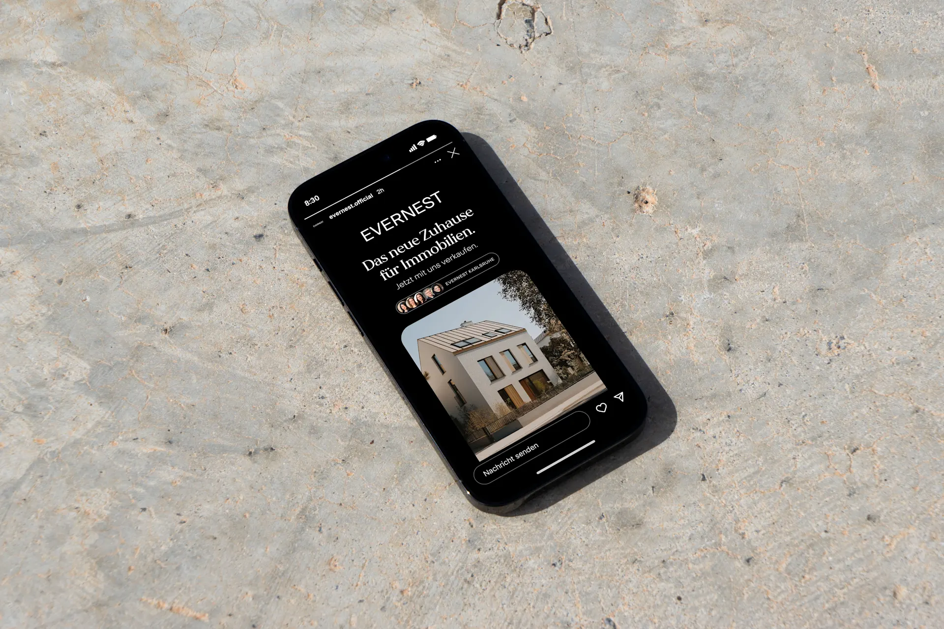 Smartphone liegt auf Betonboden und zeigt ein Haus auf seinem Bildschirm.