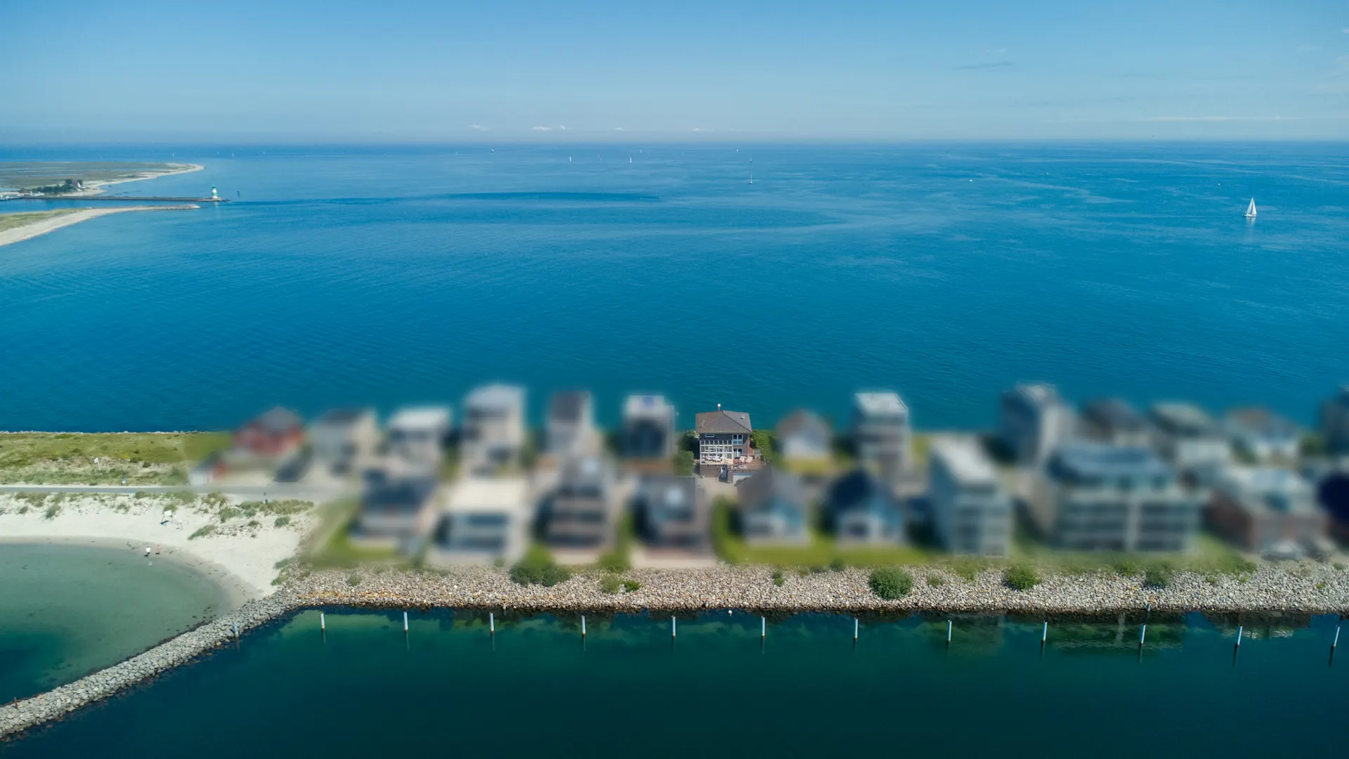 Luftaufnahme von Häusern an einer Küste mit weitem Blick auf das Meer.