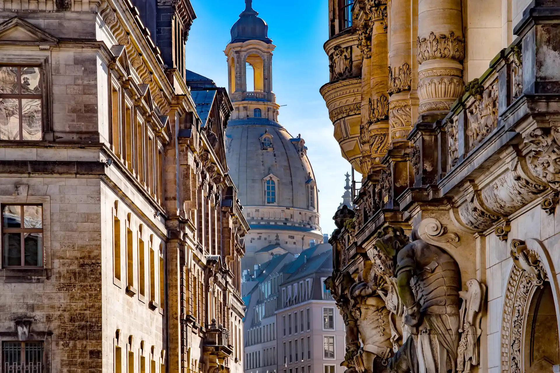 Blick auf historische Wohngebäude mit Verzierungen und Kuppel im Hintergrund.