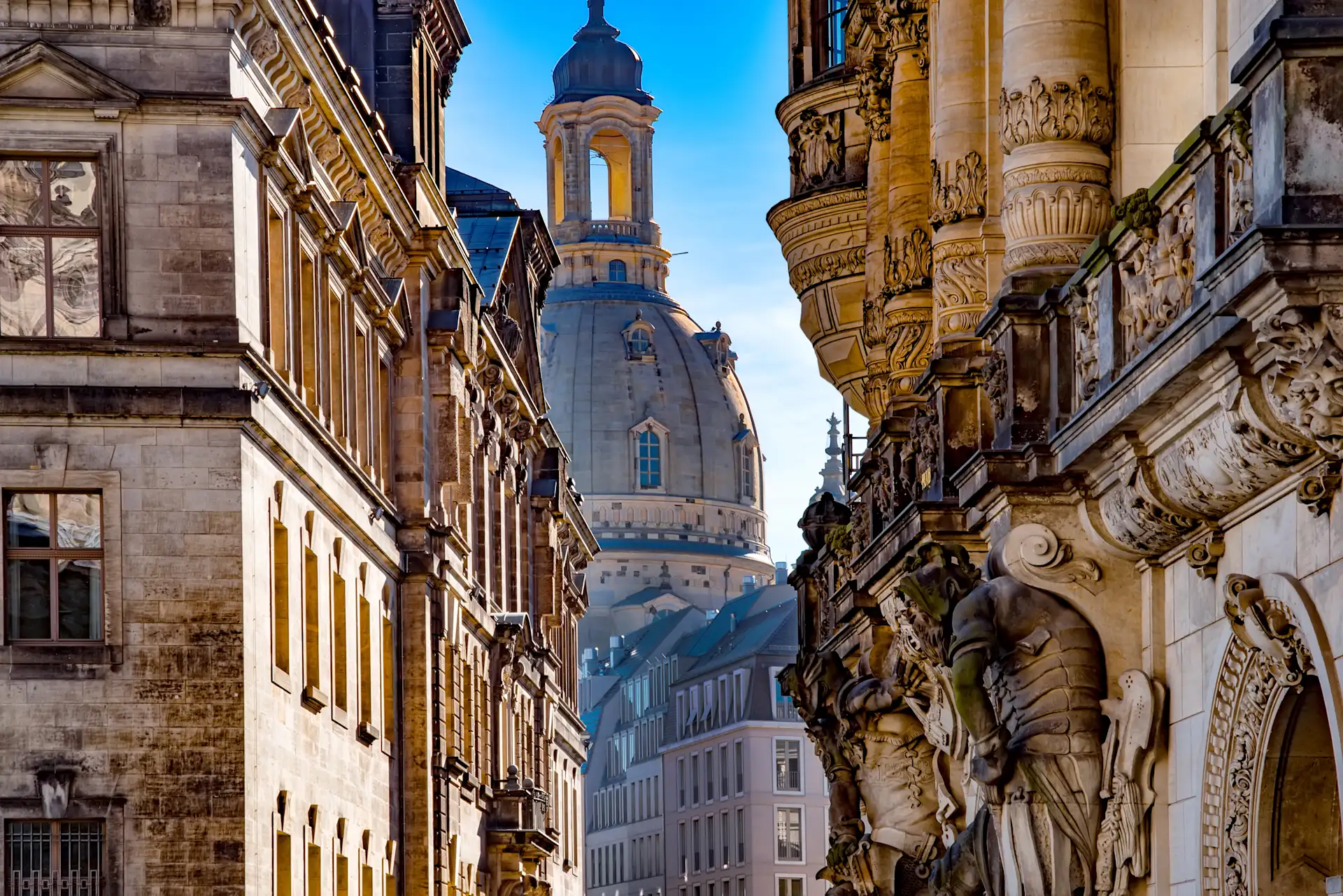 Blick auf historische Wohngebäude mit Verzierungen und Kuppel im Hintergrund.