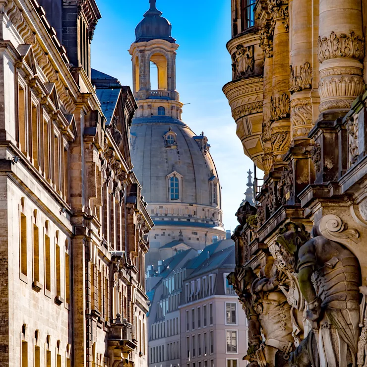 Blick auf historische Wohngebäude mit Verzierungen und Kuppel im Hintergrund.