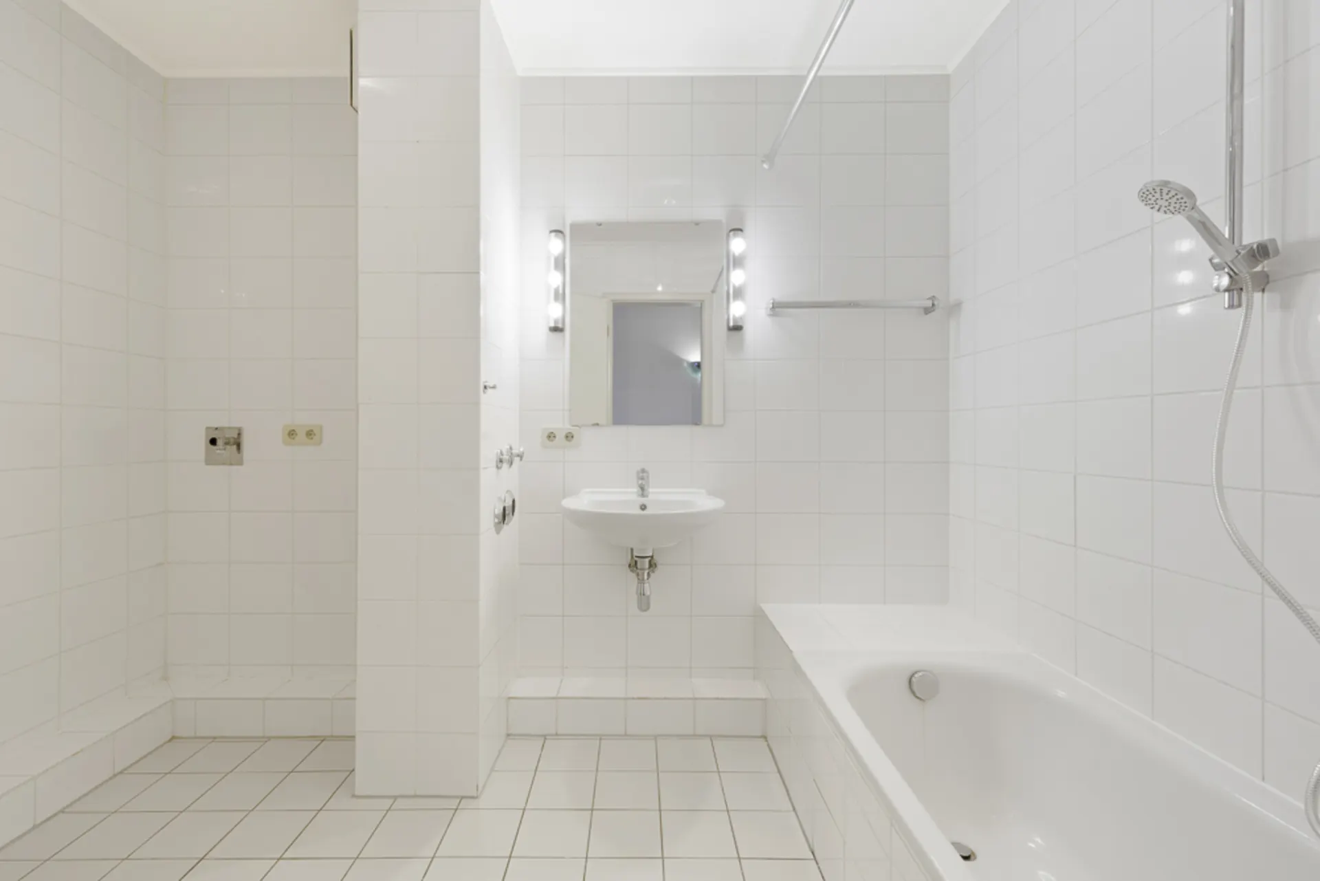 Helles Badezimmer mit Badewanne, Dusche, Waschbecken und beleuchtetem Spiegel.