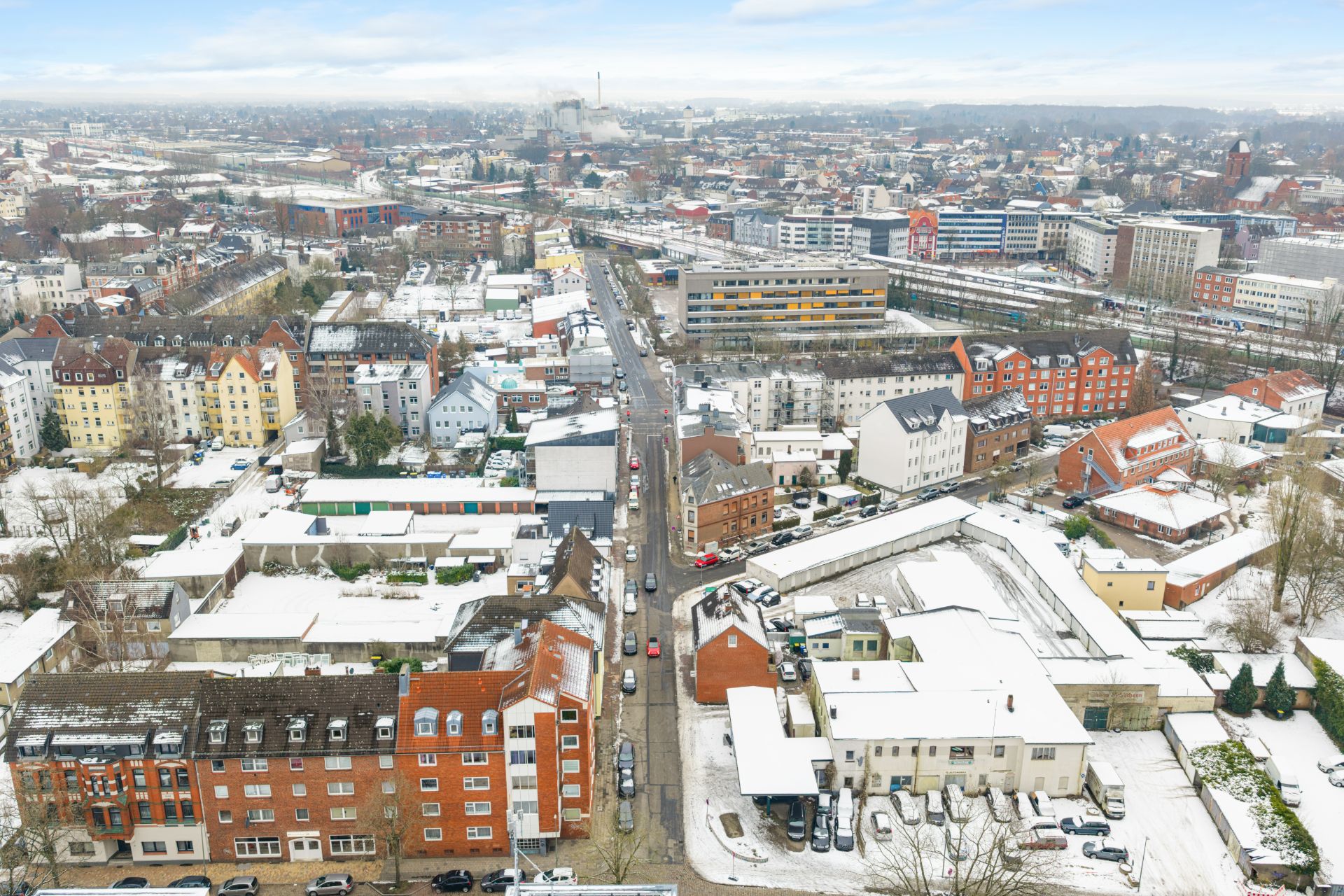 Luftaufnahme einer Wohngegend mit schneebedeckten Gebäuden und Straßen.