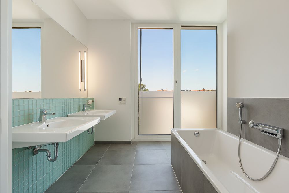 Modernes Badezimmer mit zwei Waschbecken, Badewanne und großem Fenster.