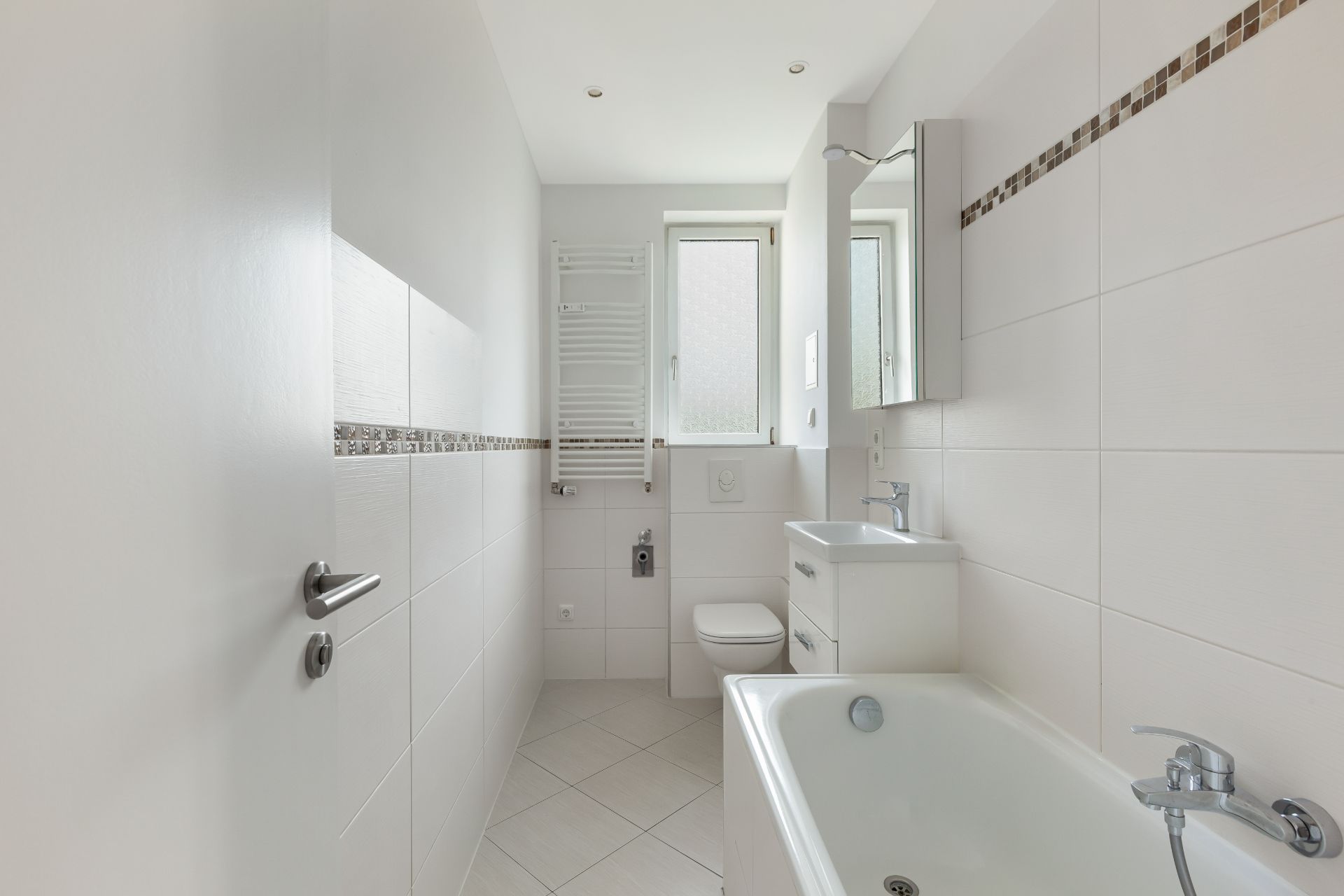Helles Badezimmer mit Badewanne, WC, Waschbecken und Fenster.