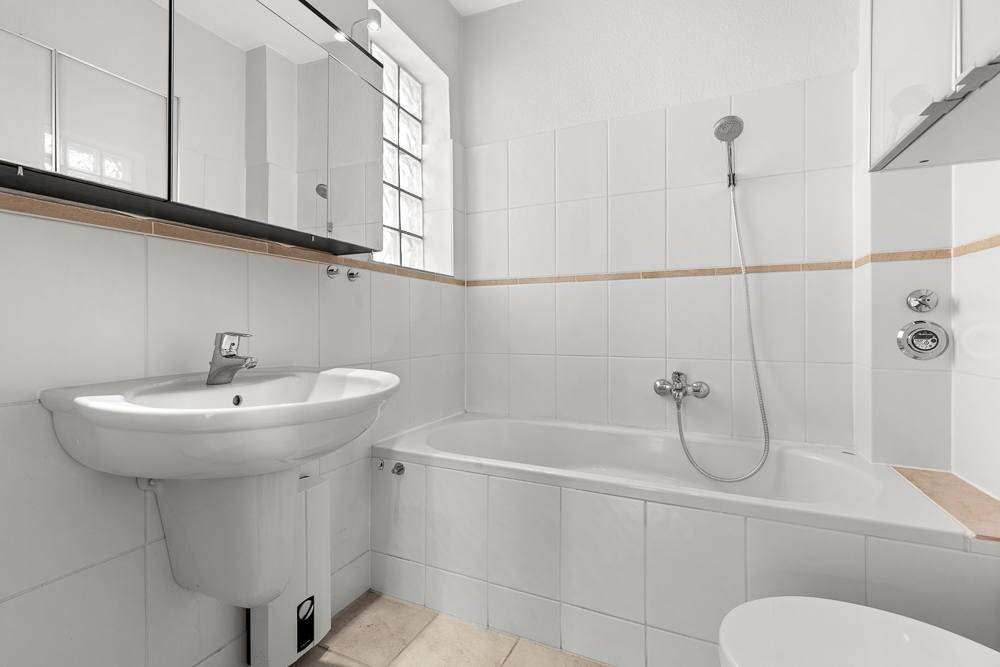 Modernes weißes Badezimmer mit Waschbecken, Badewanne und Spiegel.