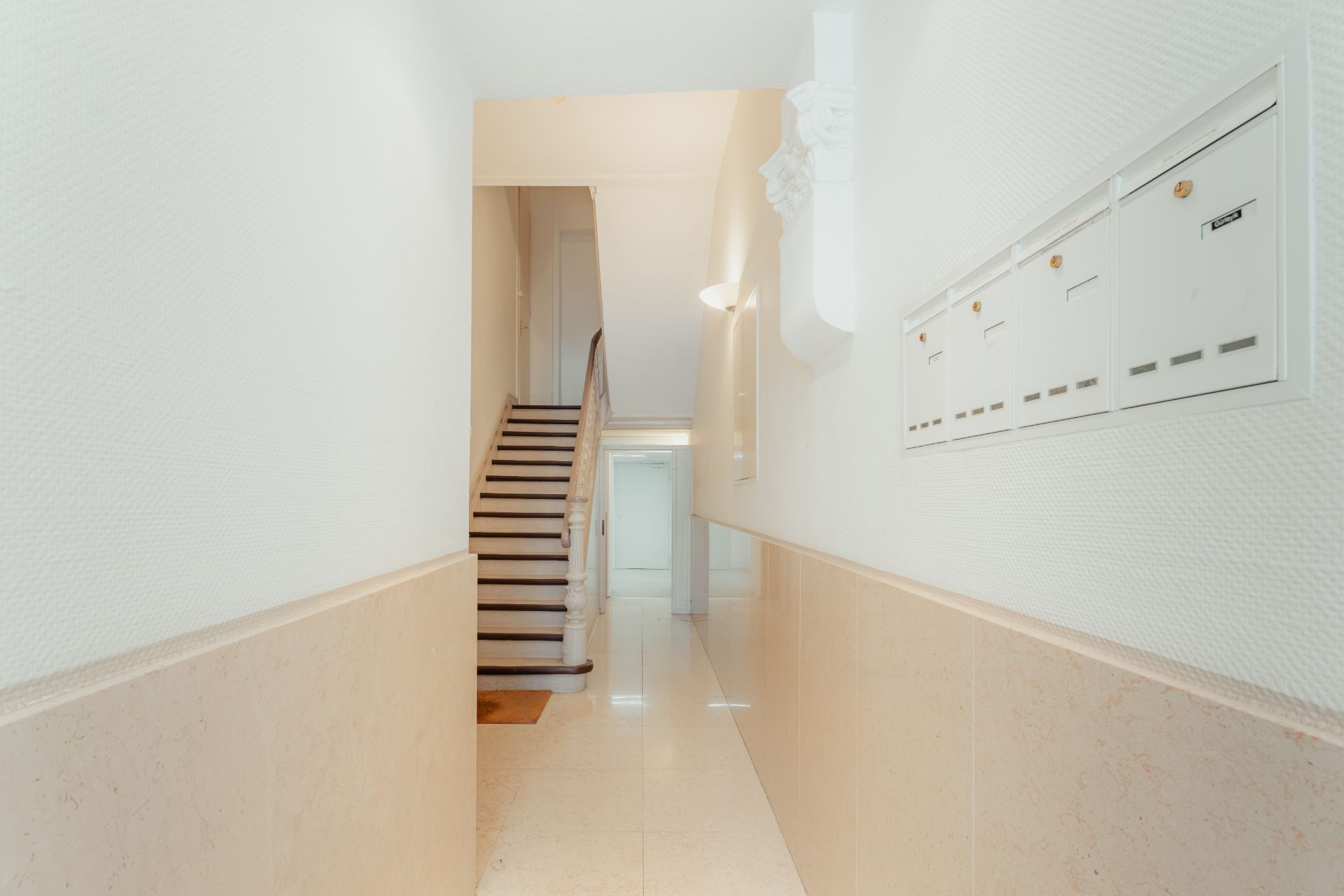Heller Flur mit Treppe und weißen Briefkästen an der Wand.