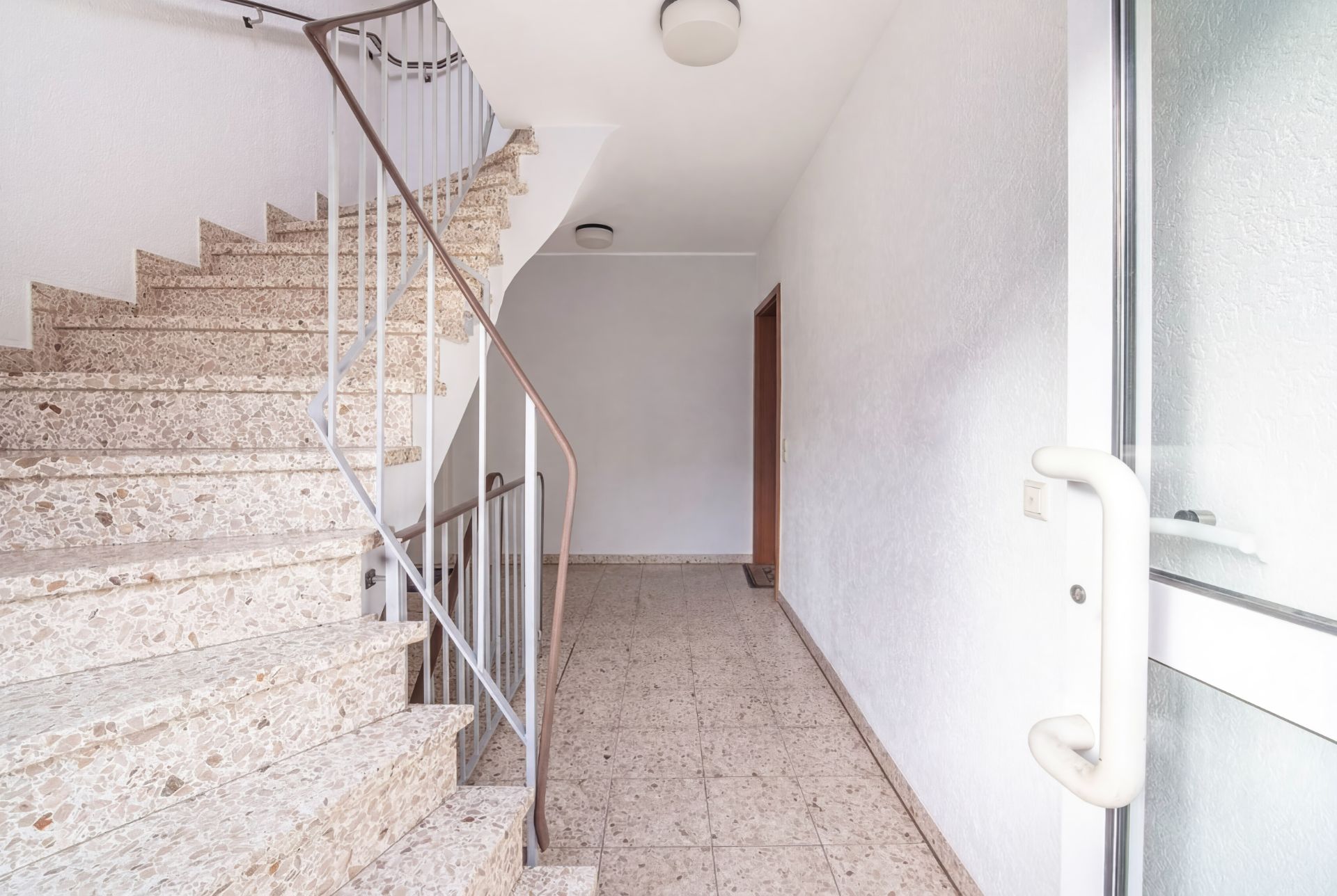Heller Eingangsbereich mit Treppe und Flur in einem Wohnhaus.