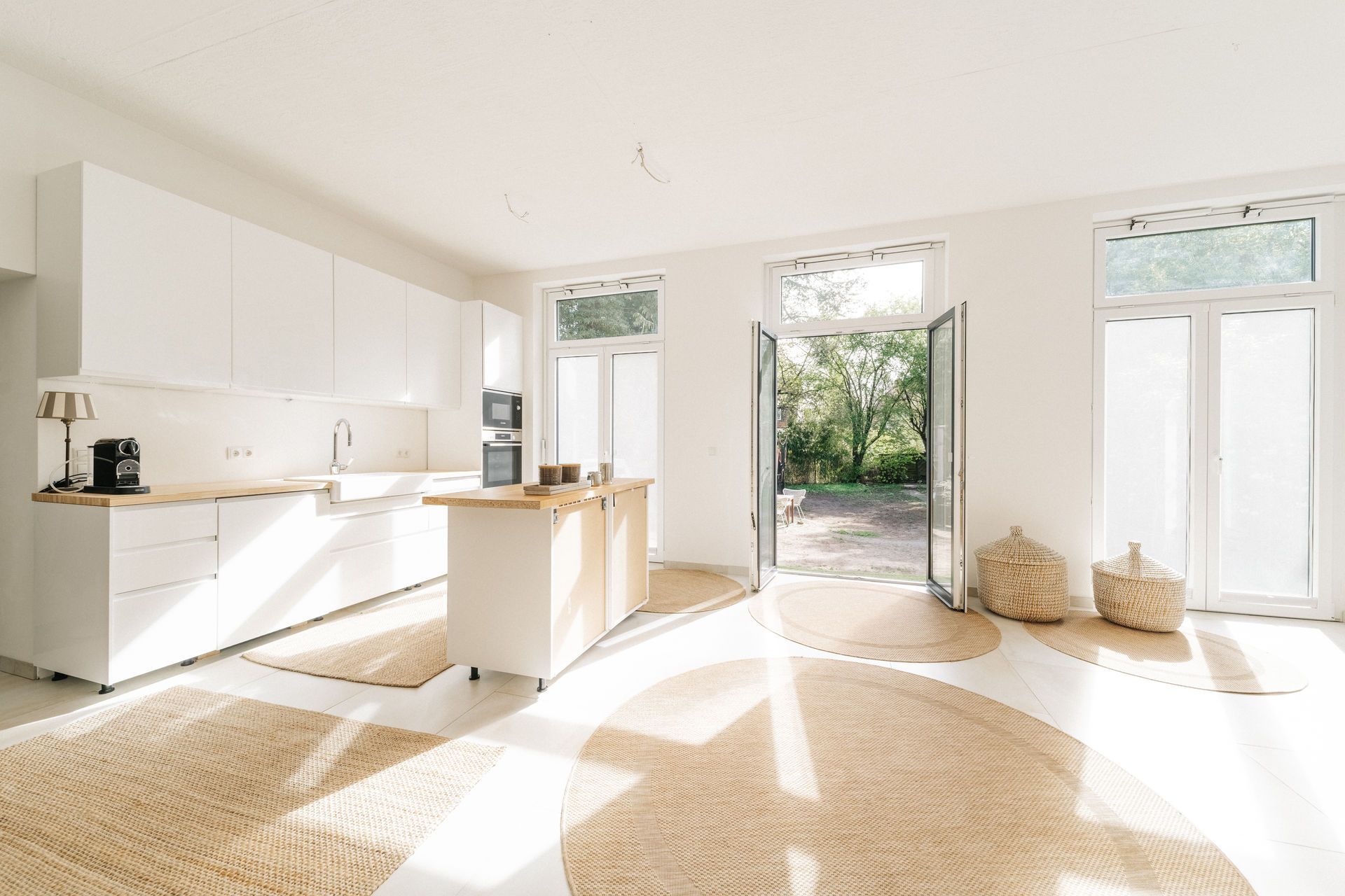 Helle moderne Küche mit Insel, großen Fenstern und Türen zum Garten.