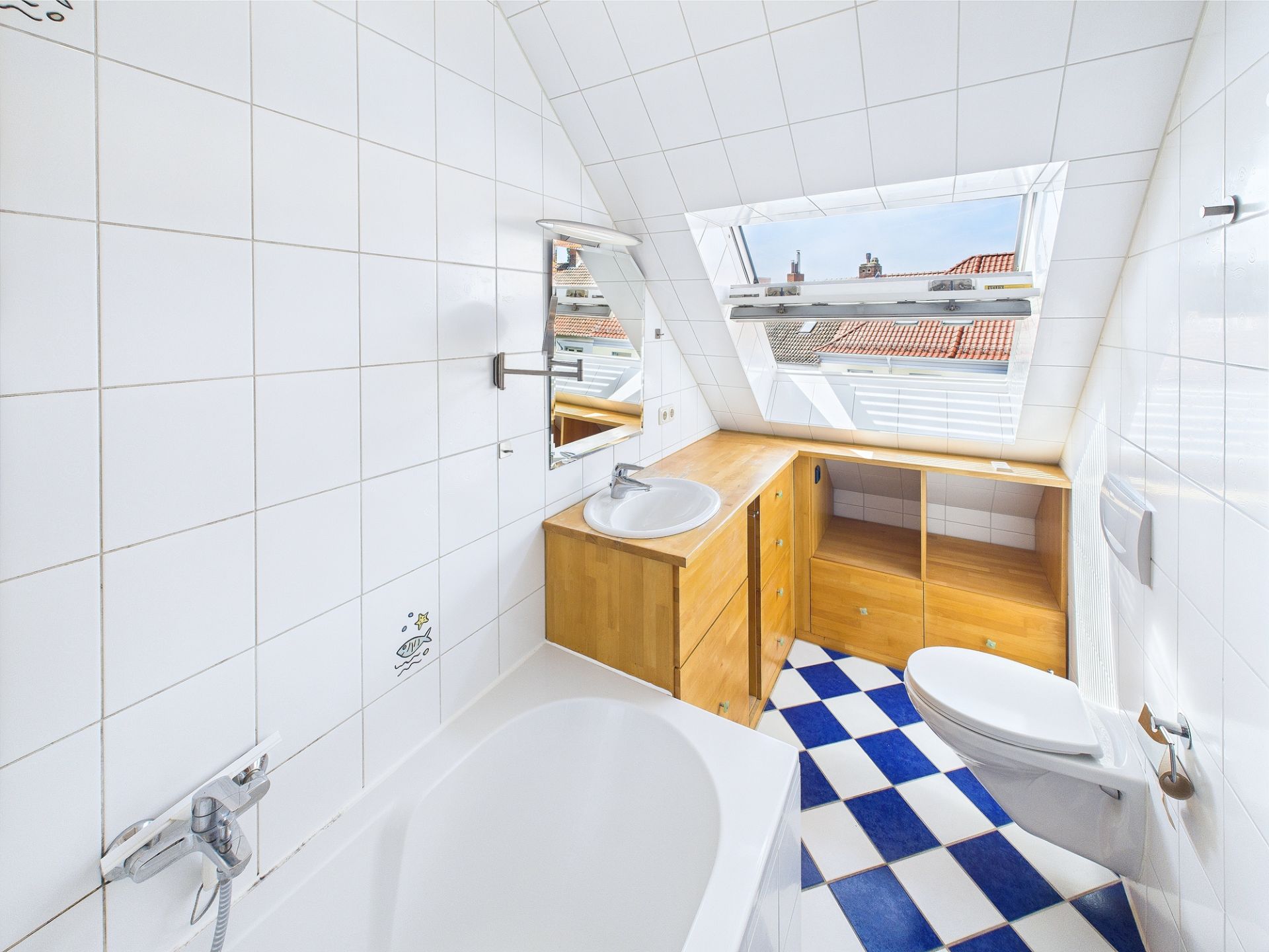 Helles Badezimmer mit Badewanne, Waschbecken, WC und großem Fenster im Dachgeschoss.