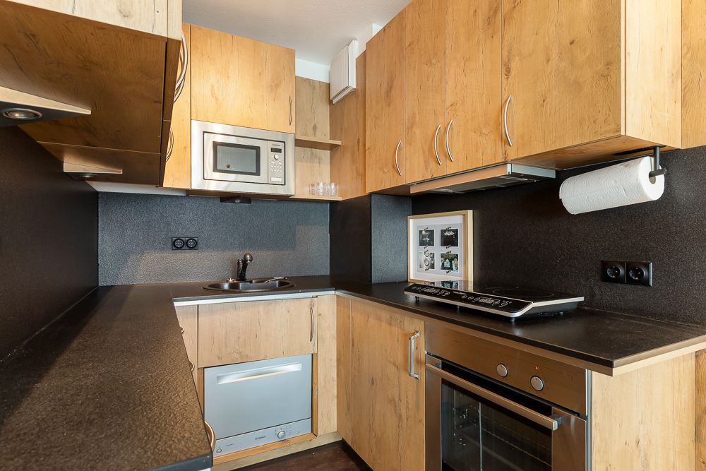 Moderne Einbauküche mit Holzfronten, Herd, Ofen, Mikrowelle und Spülmaschine.