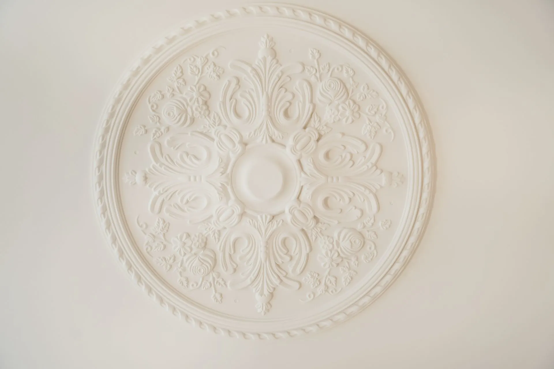 Runde, verzierte Stuckrosette an einer weißen Decke.