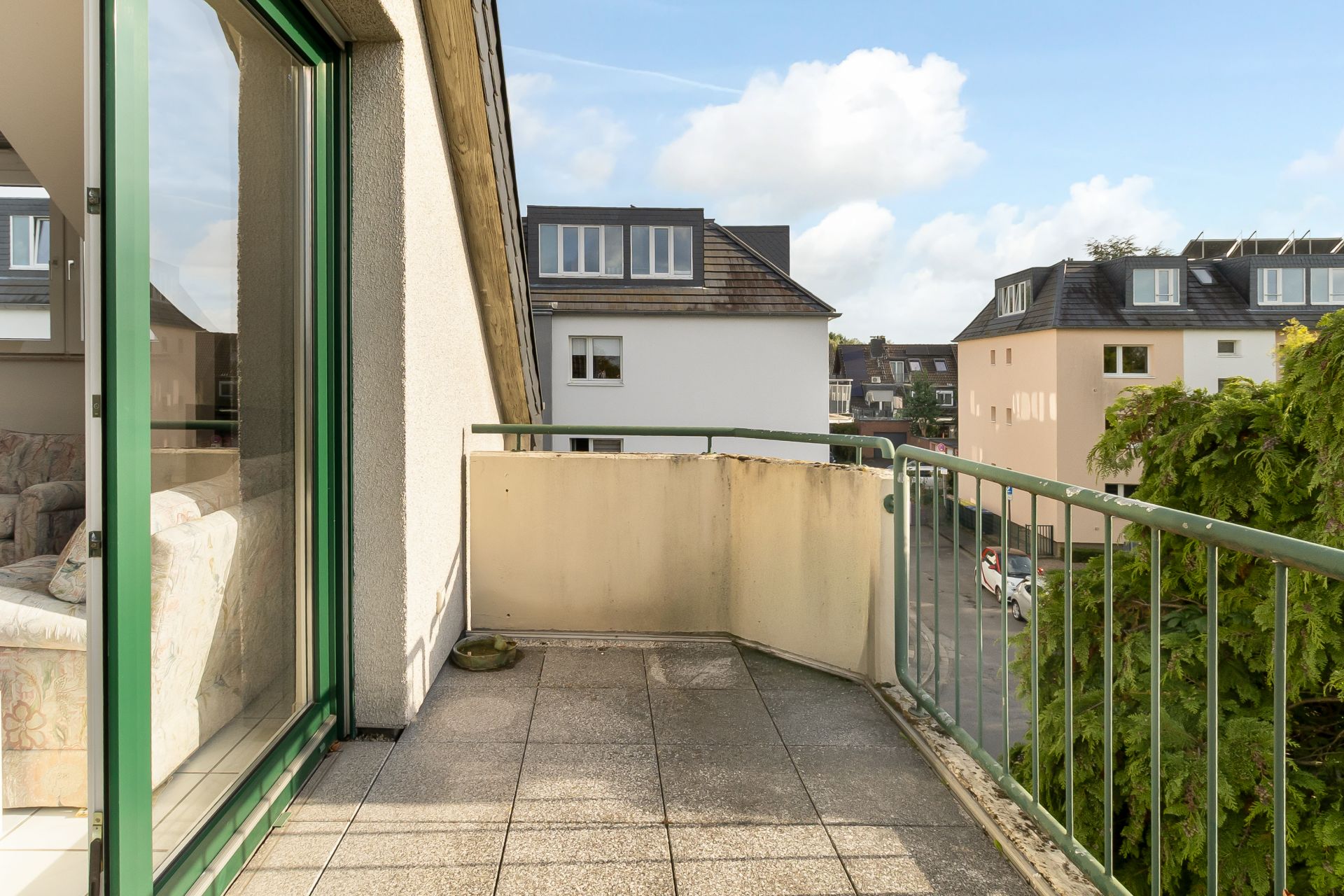 Balkon mit grünem Geländer und Ausblick auf benachbarte Wohngebäude.