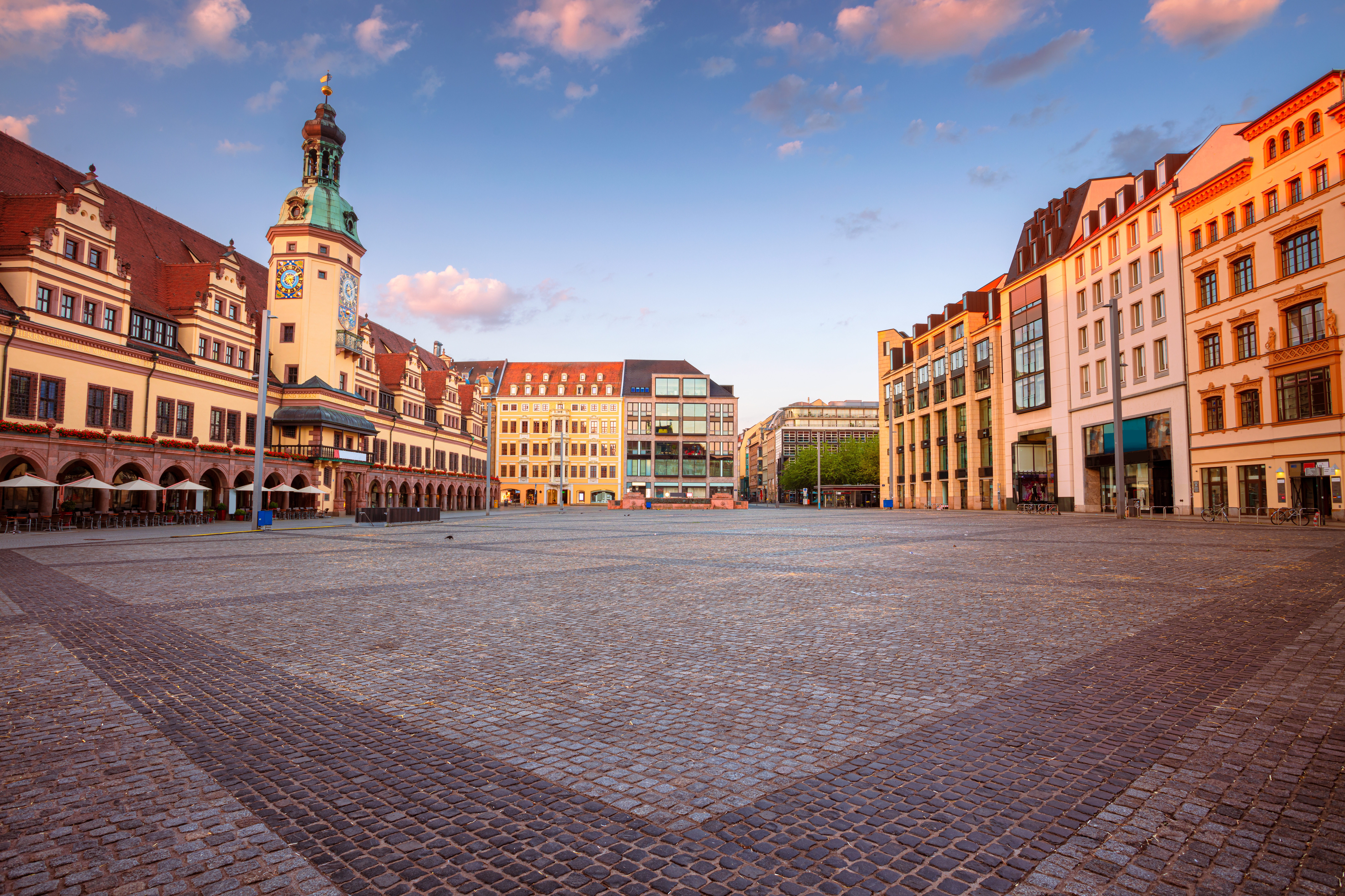 Großer, leerer Platz mit historischen und modernen Gebäuden bei Sonnenuntergang.