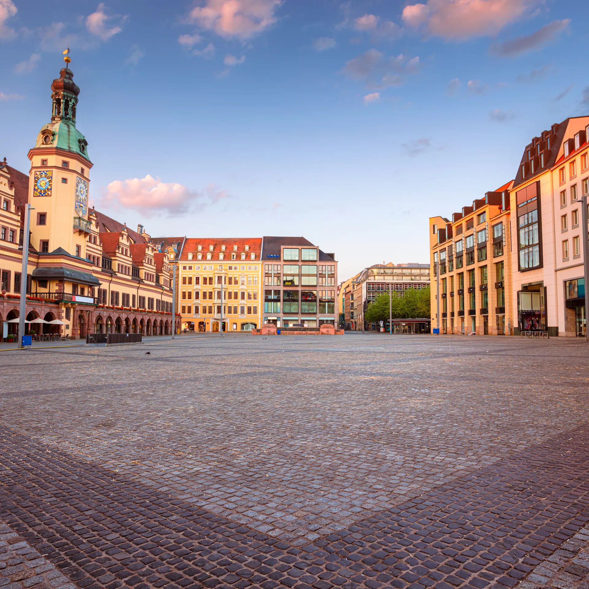 Großer, leerer Platz mit historischen und modernen Gebäuden bei Sonnenuntergang.