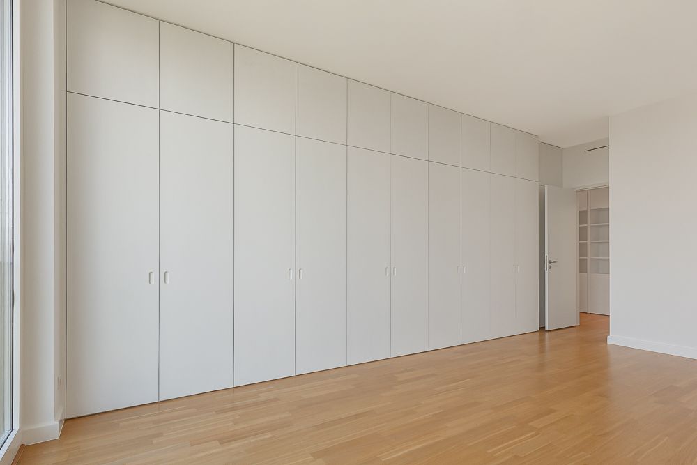 Leerer Raum mit Einbauschränken, Parkettboden und offener Tür.