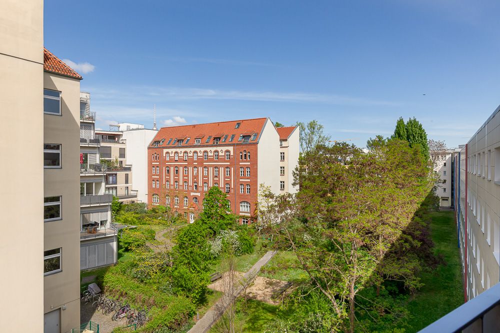 Blick auf einen begrünten Innenhof mit Wegen, umgeben von Wohngebäuden und einem roten Backsteinhaus.