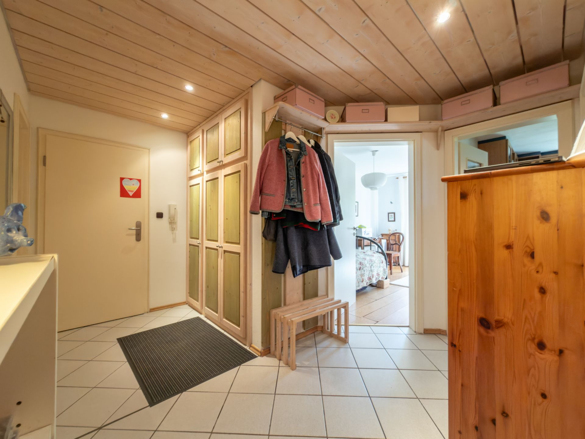Heller Flur mit Holzmöbeln, Garderobe, Sitzbank und Zugang zu weiteren Zimmern.