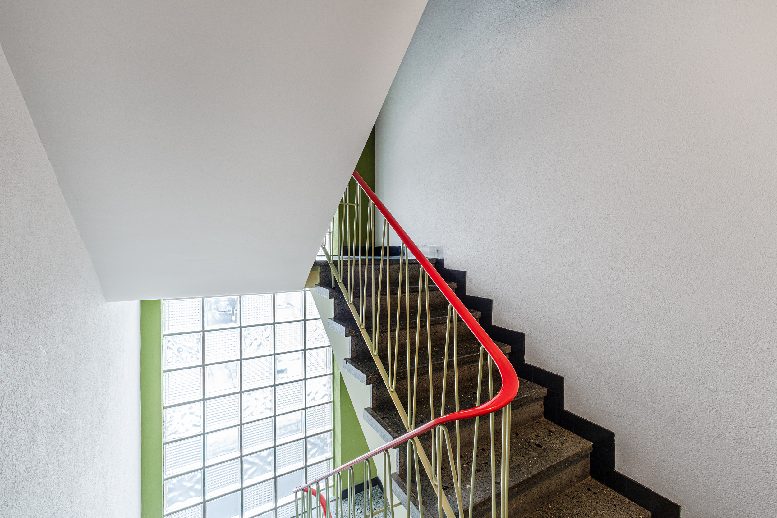 Staircase mit rotem Geländer und Glasbaustein-Fenster im Treppenhaus.