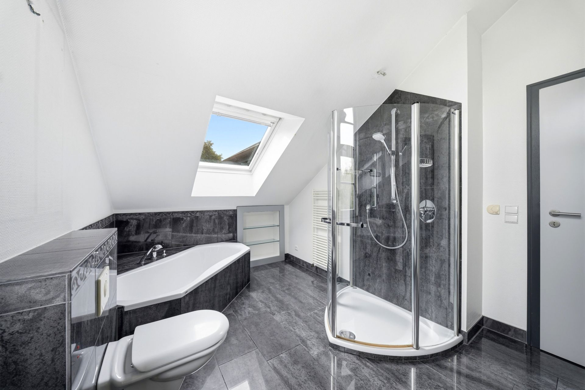 Modernes Badezimmer mit Eckbadewanne, Dusche und Dachfenster.