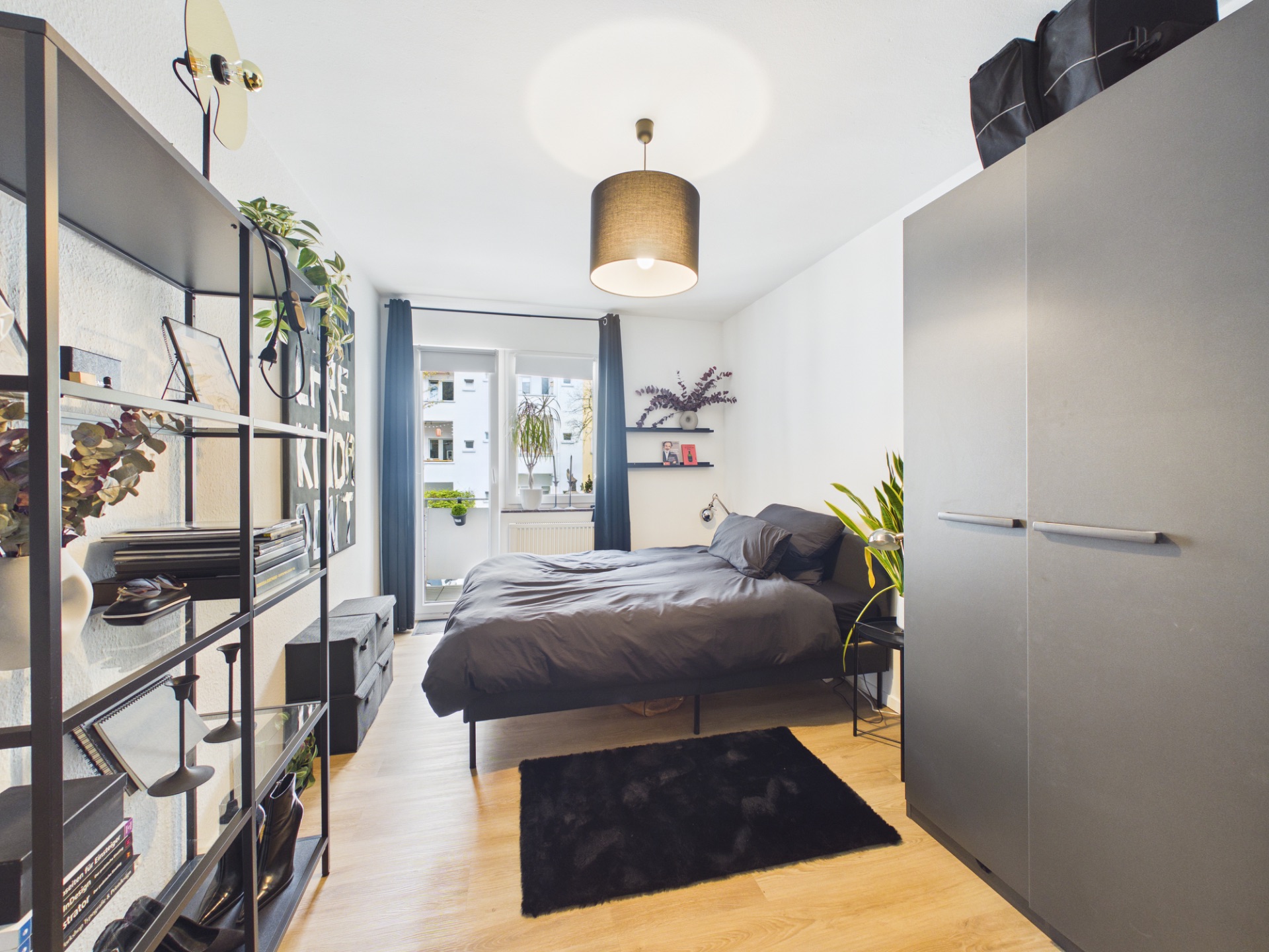 Modernes Schlafzimmer mit Doppelbett, Kleiderschrank, Regal und Zugang zu einem Balkon.