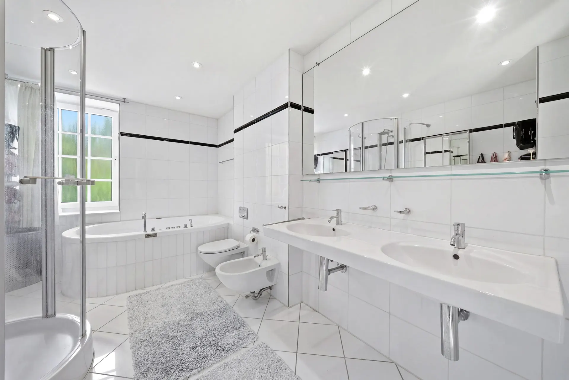 Helles, modernes Badezimmer mit Badewanne, Dusche, Doppelwaschbecken und großem Spiegel.